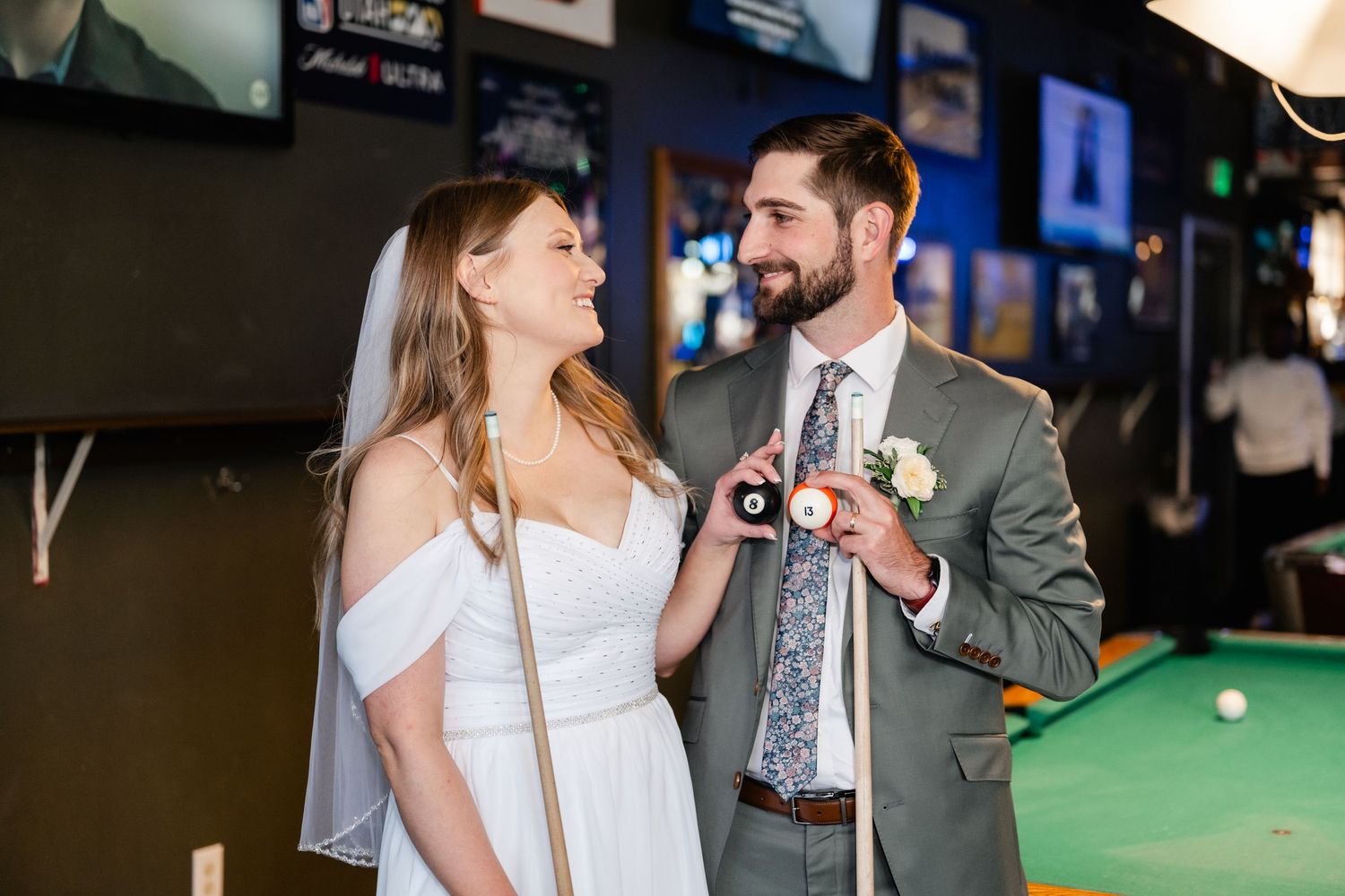 A couple shares a romantic moment in a bar with pool tables and neon lights.