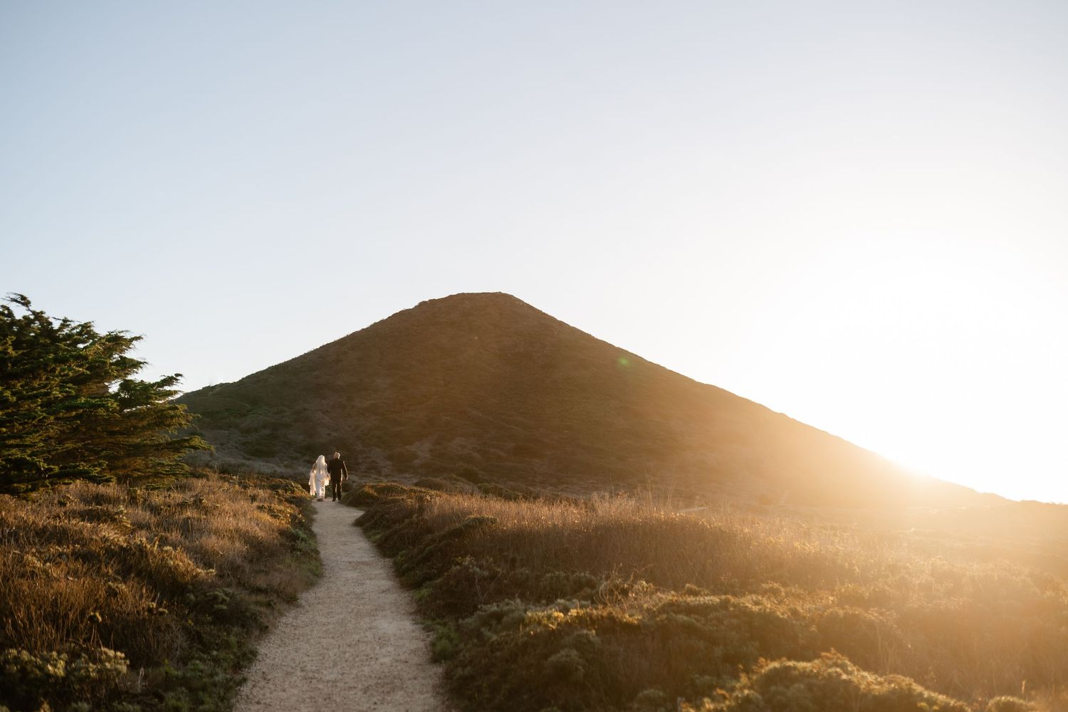 Scenic coastal trail at sunset with mountain silhouette in background.