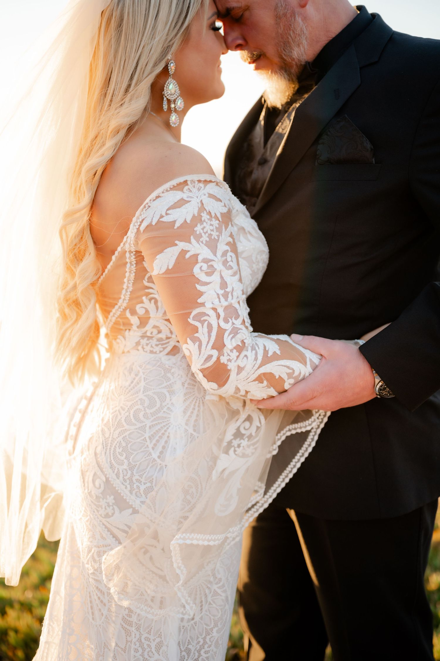 Close-up of intricate lace details on a wedding dress backlit by golden sunlight.