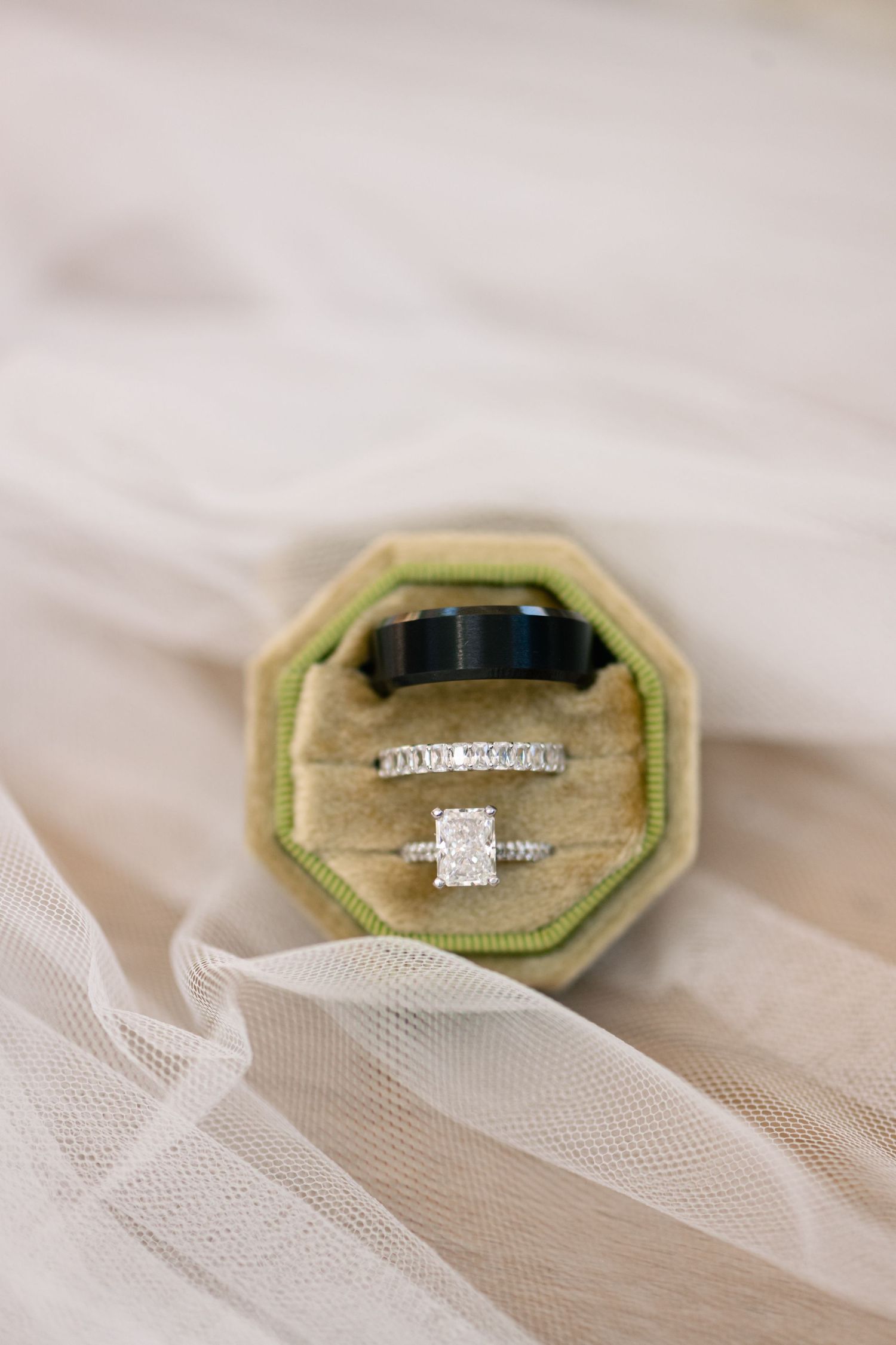 Wedding rings displayed in a vintage green velvet ring box on delicate tulle fabric.