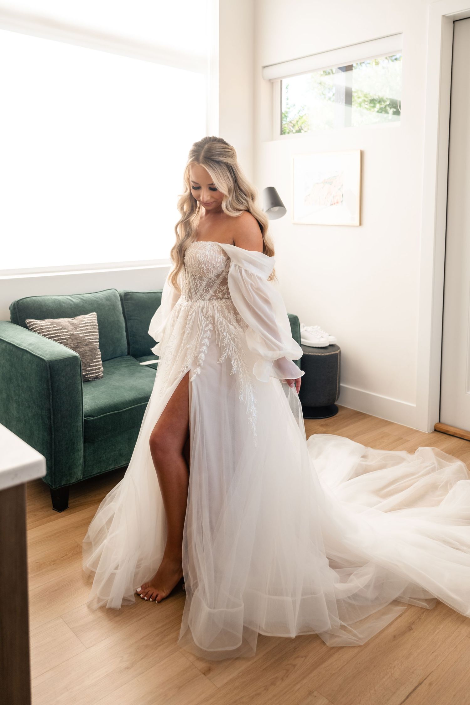 Flowing white wedding gown with lace details and dramatic train displayed in modern room.