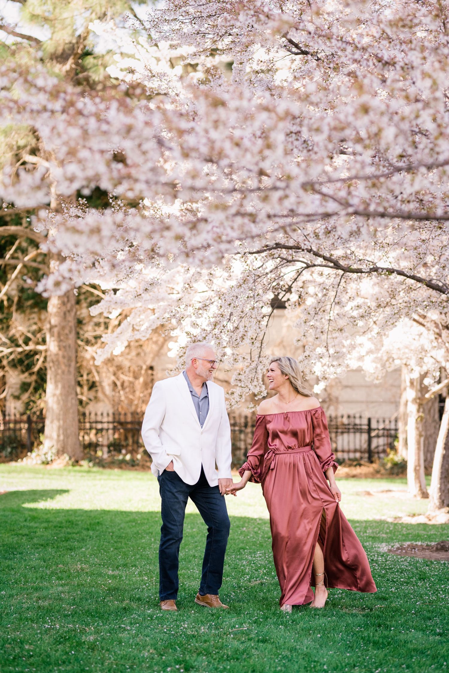 Engaged couple holding hands at the Capitol cherry blossoms by timeless wedding photographer Coley Cook