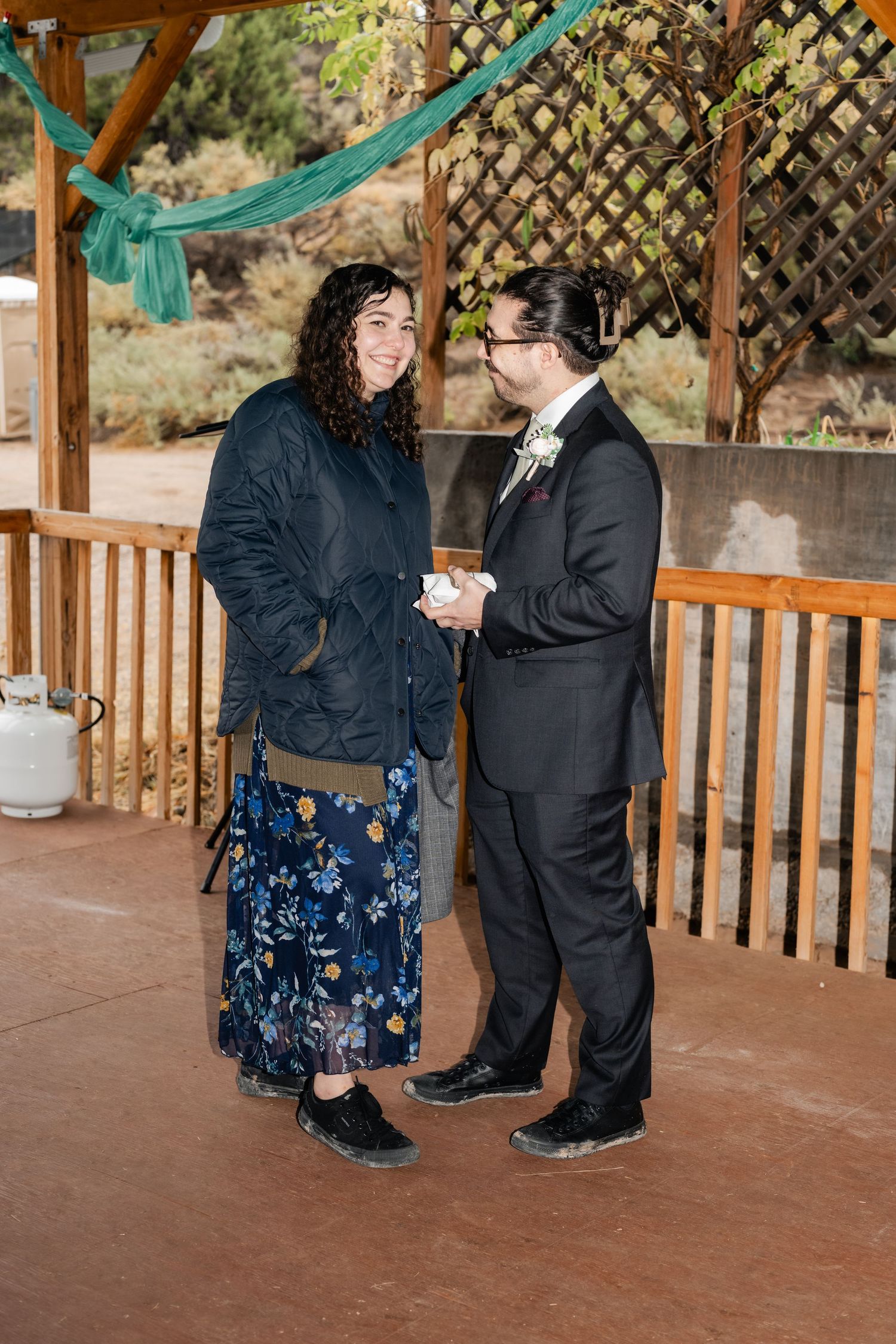 Two people sharing a moment together on a covered deck with teal decorations overhead.