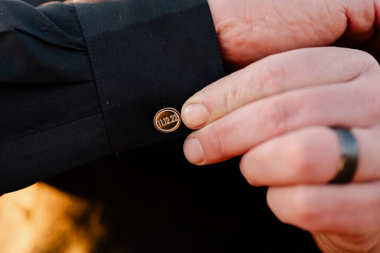 Close-up details of wedding rings and hands against a dark background.