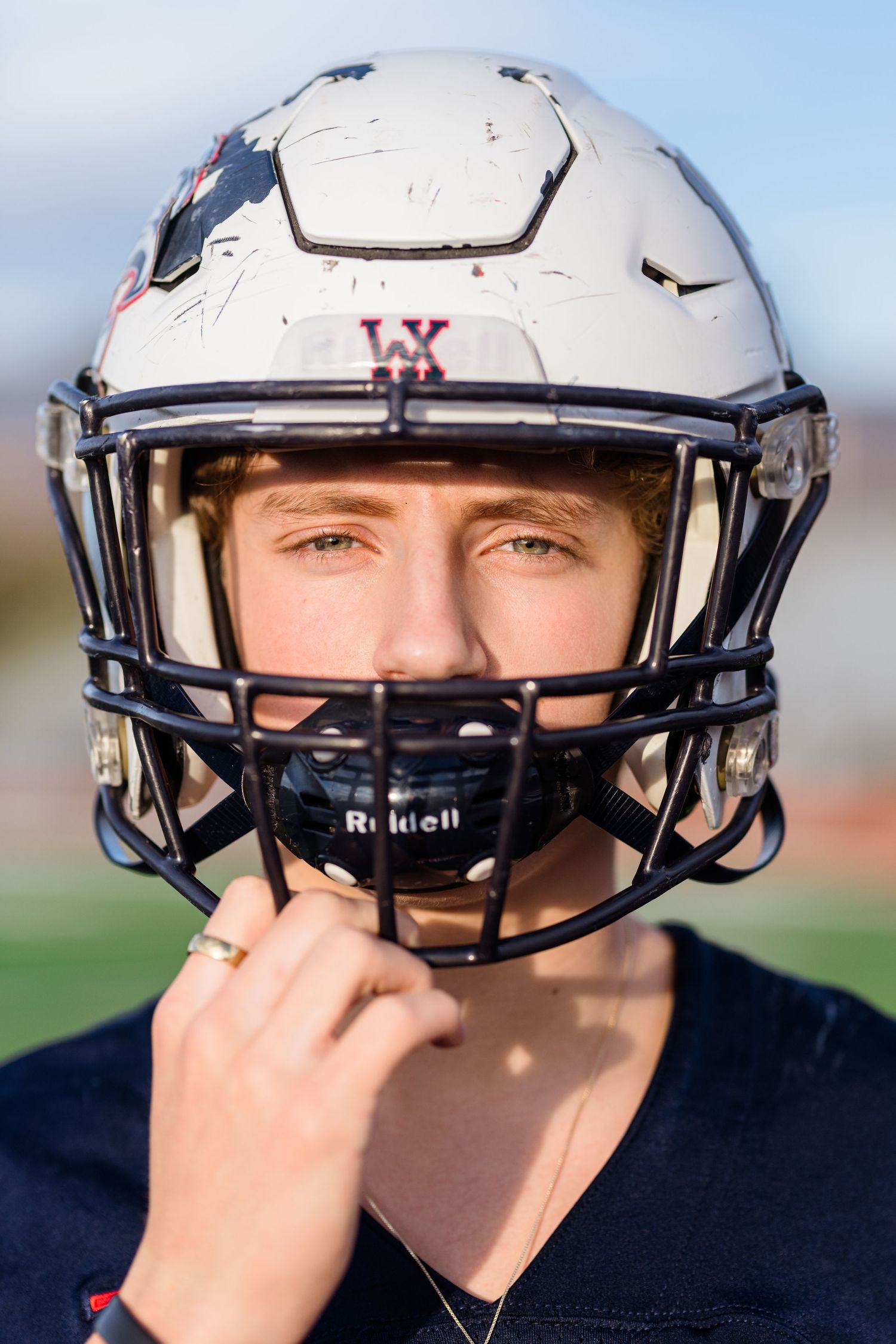 A series of photos showing a football player adjusting their white helmet with a navy facemask in different positions.