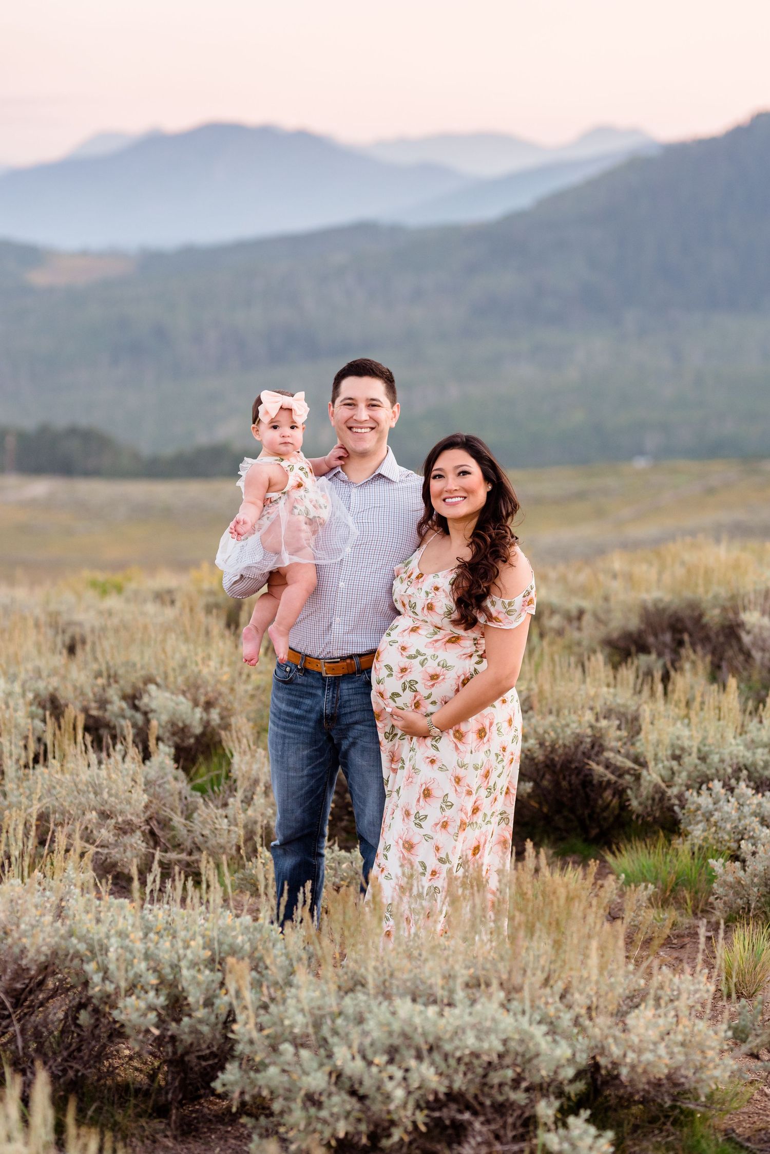 Family shares joyful moments while posing together in a mountain meadow filled with sagebrush at dusk.