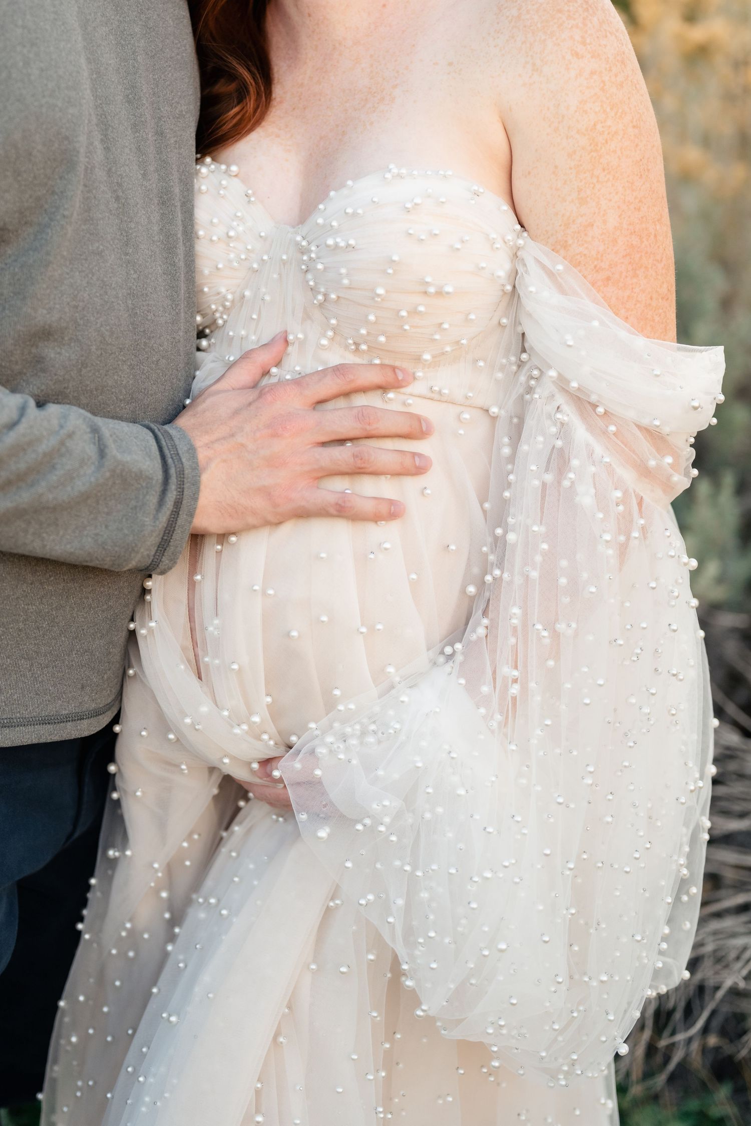 Close-up sequence of hands gently touching delicate white beaded wedding dress fabric with sparkly embellishments.