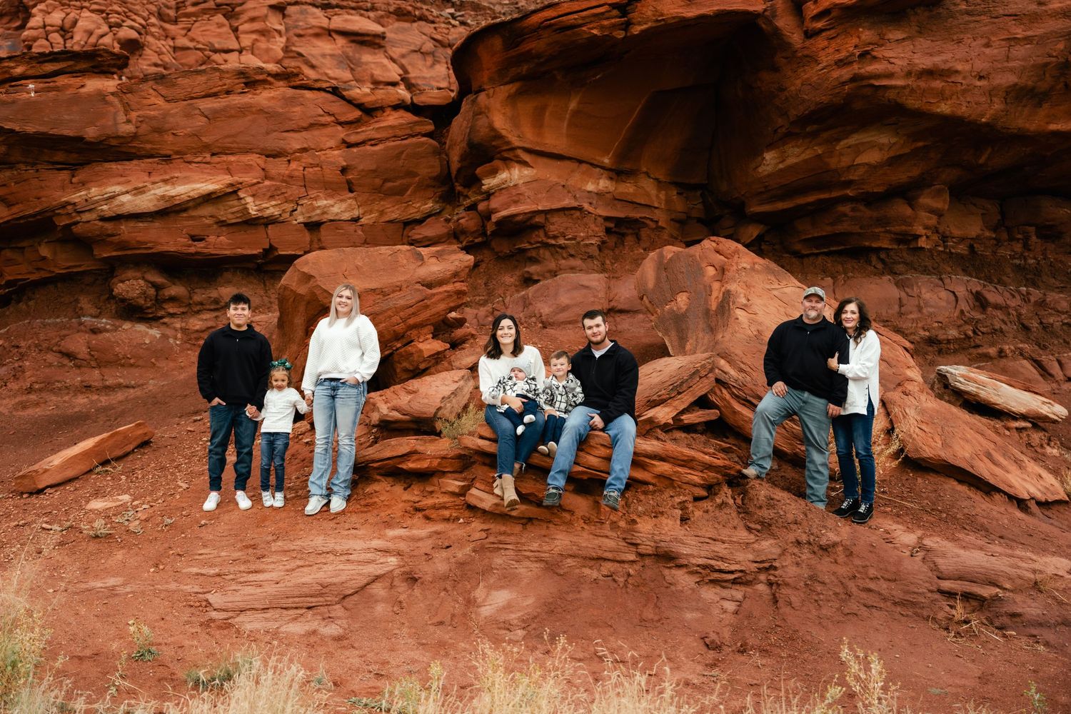 A group sits on red rock formations in an outdoor desert landscape with multiple similar poses and compositions.