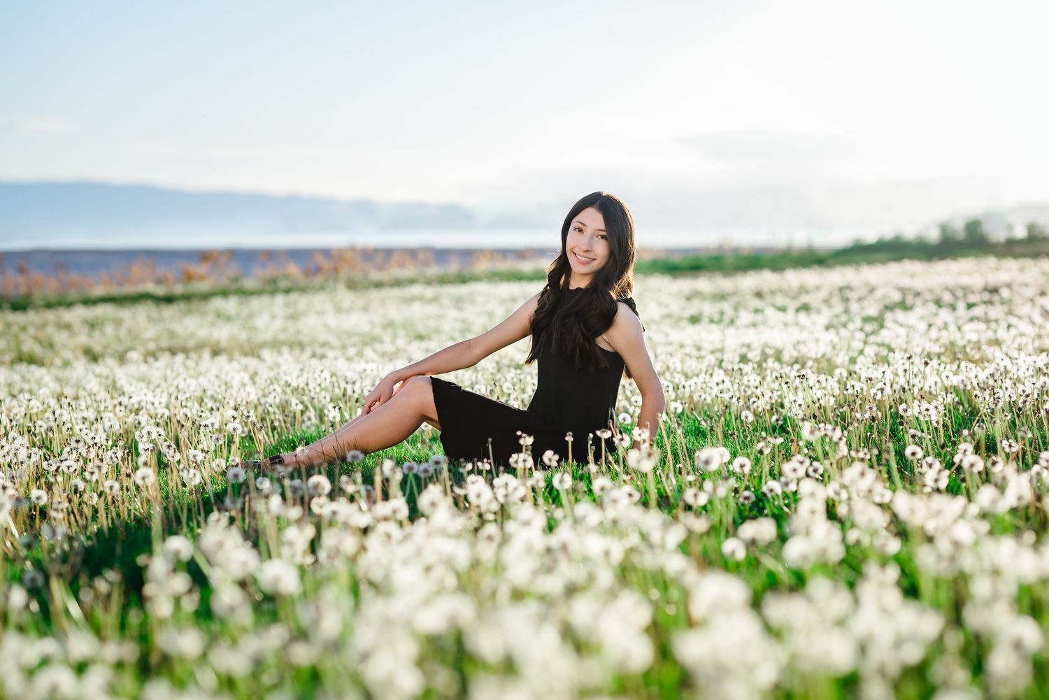 A person in a black outfit lies peacefully in a vast field of blooming white flowers on a sunny spring day.