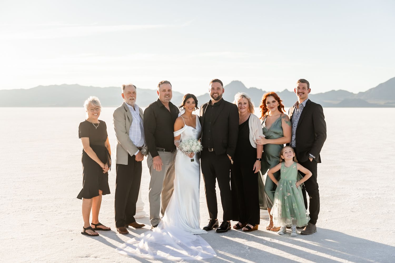 Wedding party and guests gathered on salt flats for group photos.