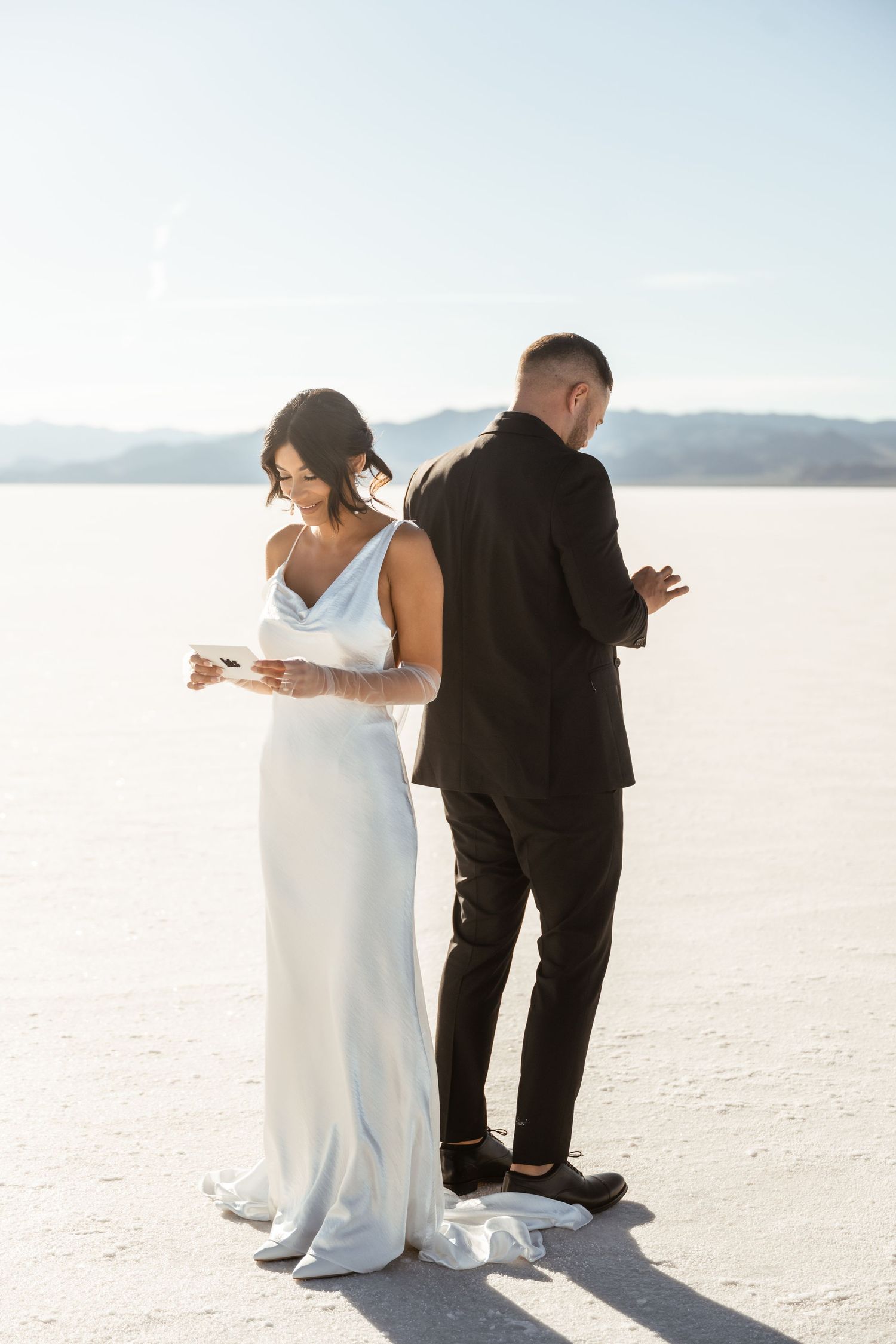 Couple in formal attire creating artistic poses against stark white salt flats.