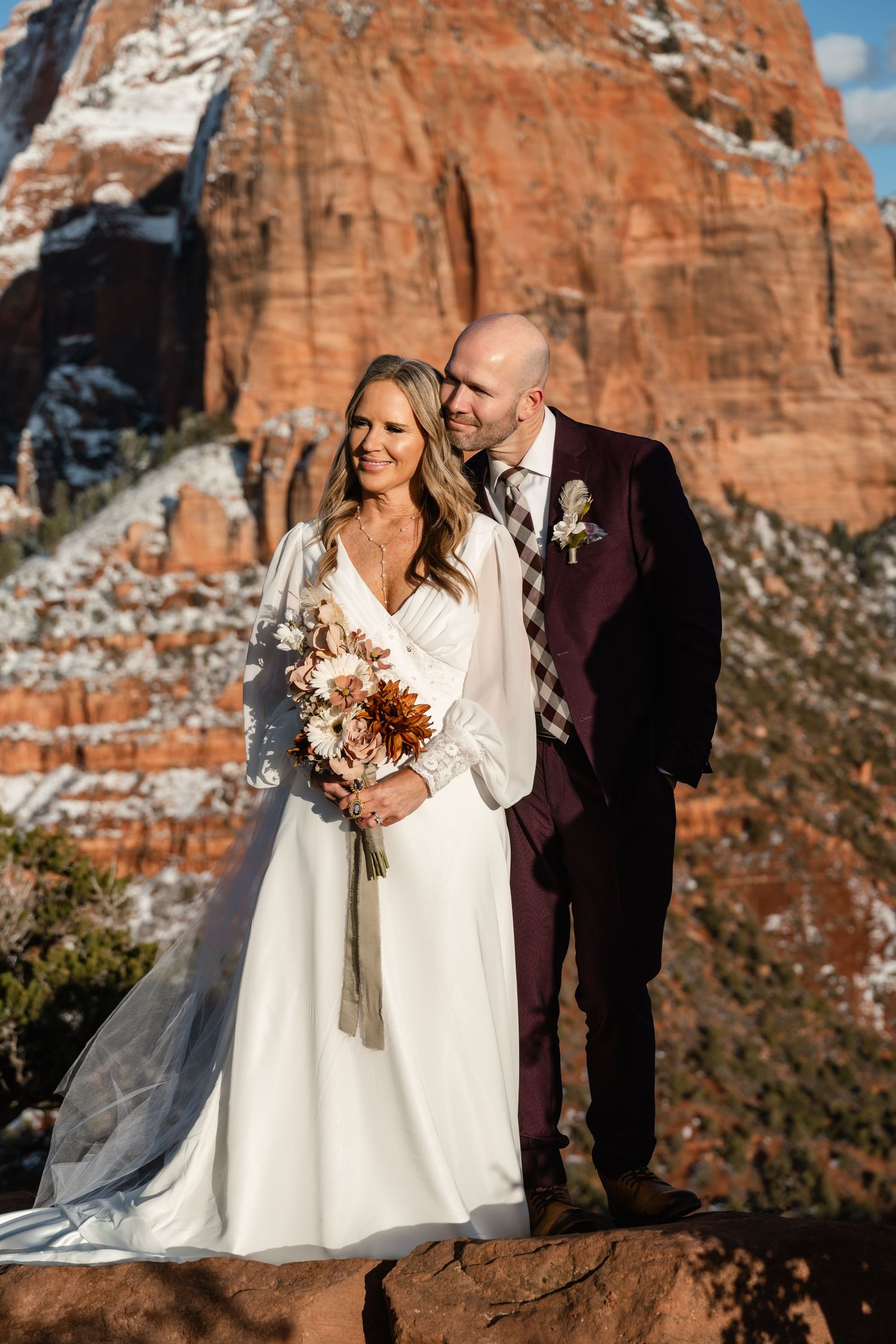 A couple celebrates their wedding against stunning red rock cliffs during golden hour.
