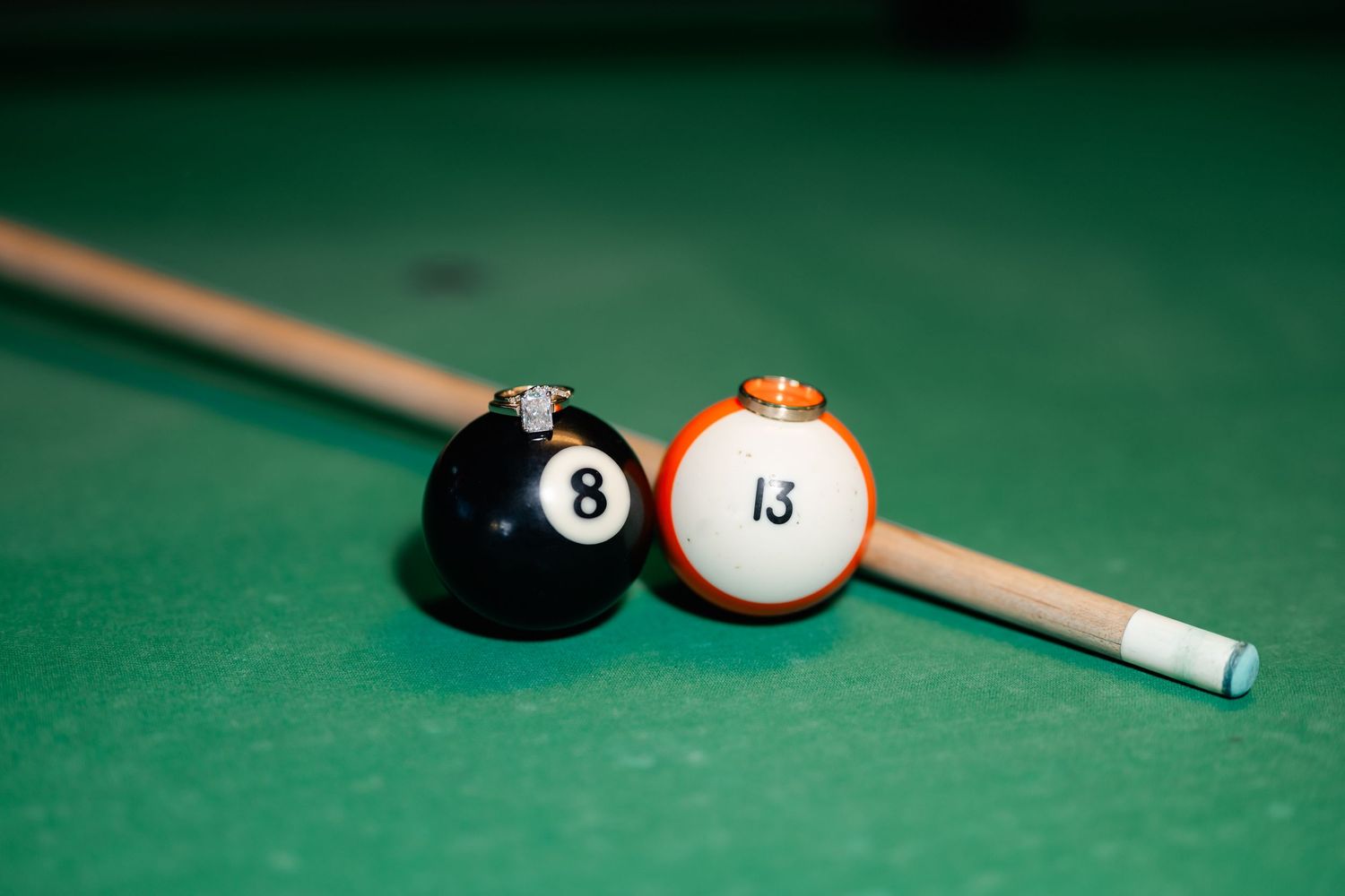 Close-up shot of pool balls and cue stick on green felt table.