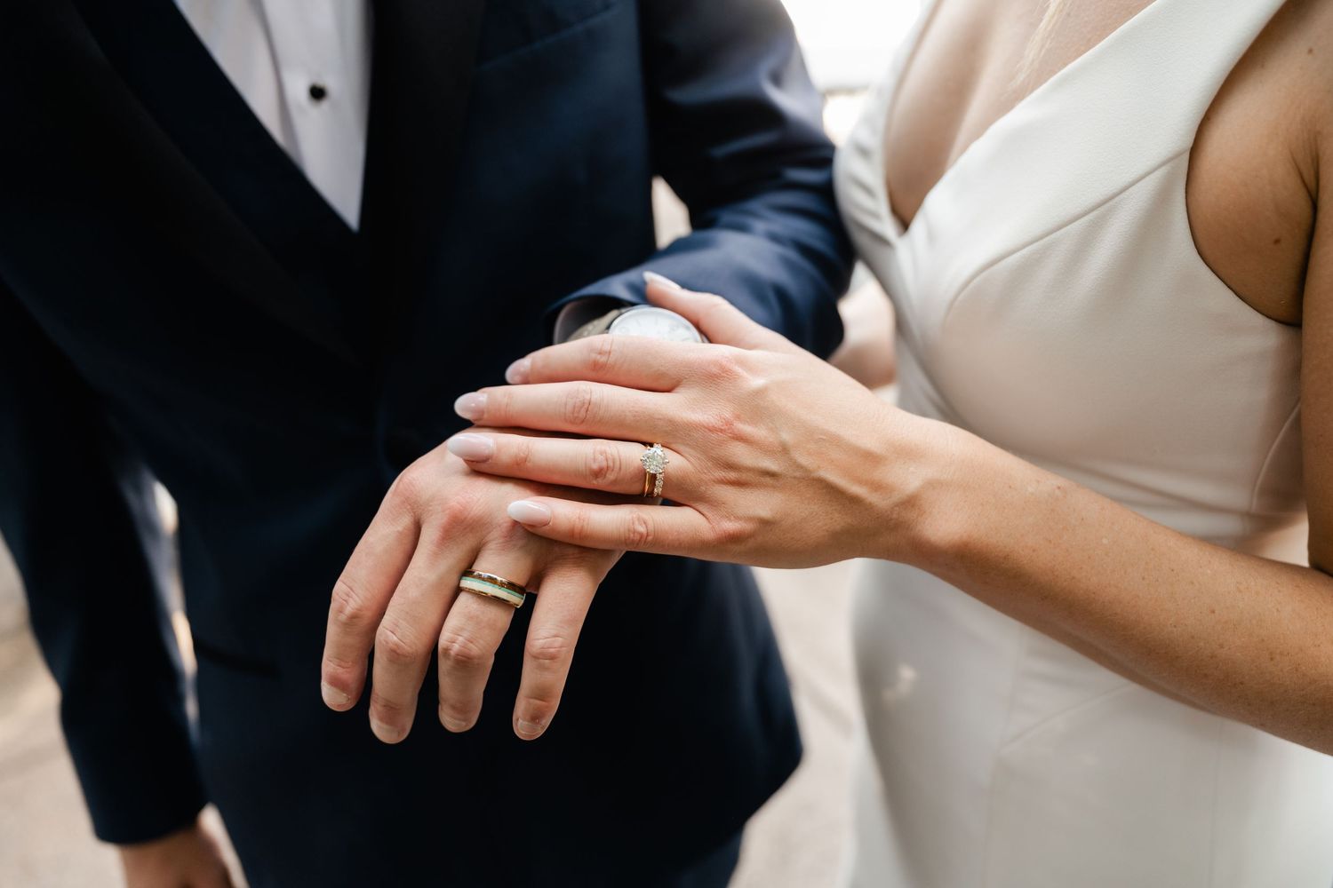 Close-up view of hands exchanging wedding rings during an intimate ceremony.