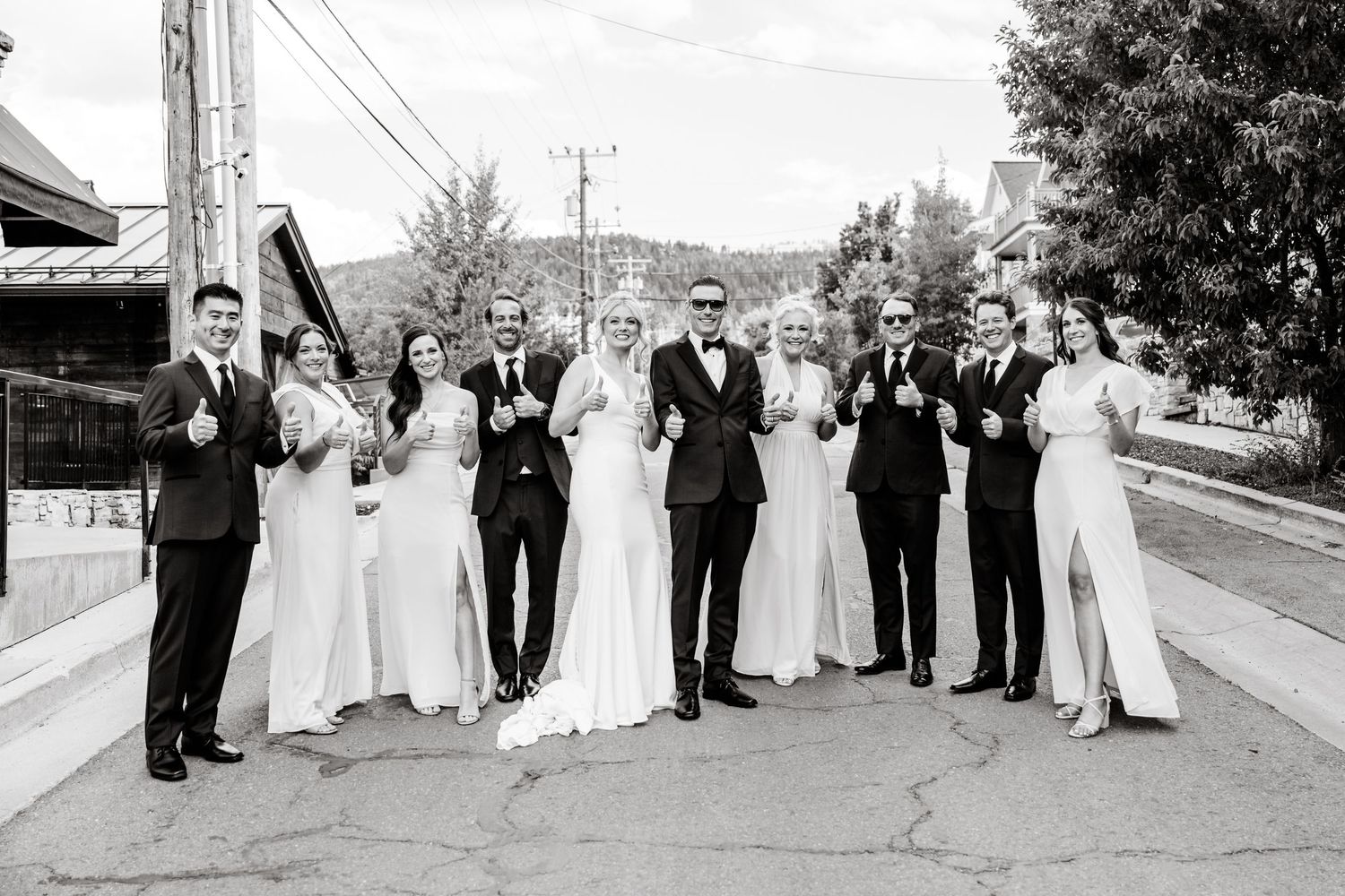 A black and white panoramic photo sequence shows a wedding party posing together on a street.