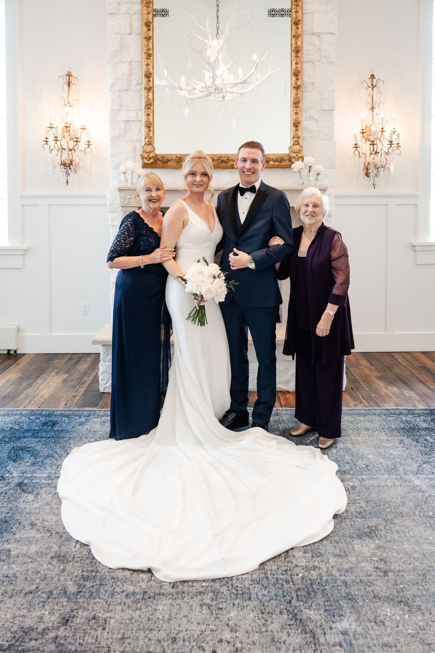 A bride in a flowing white gown shares joyful candid moments with wedding party members in an elegant ballroom setting.