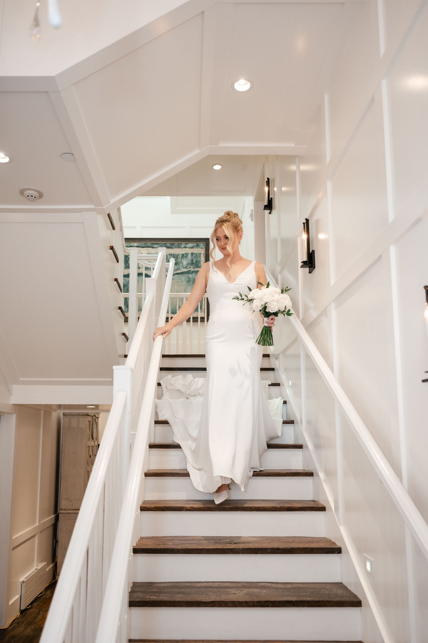 Sequence showing someone descending white stairs in a flowing wedding dress.