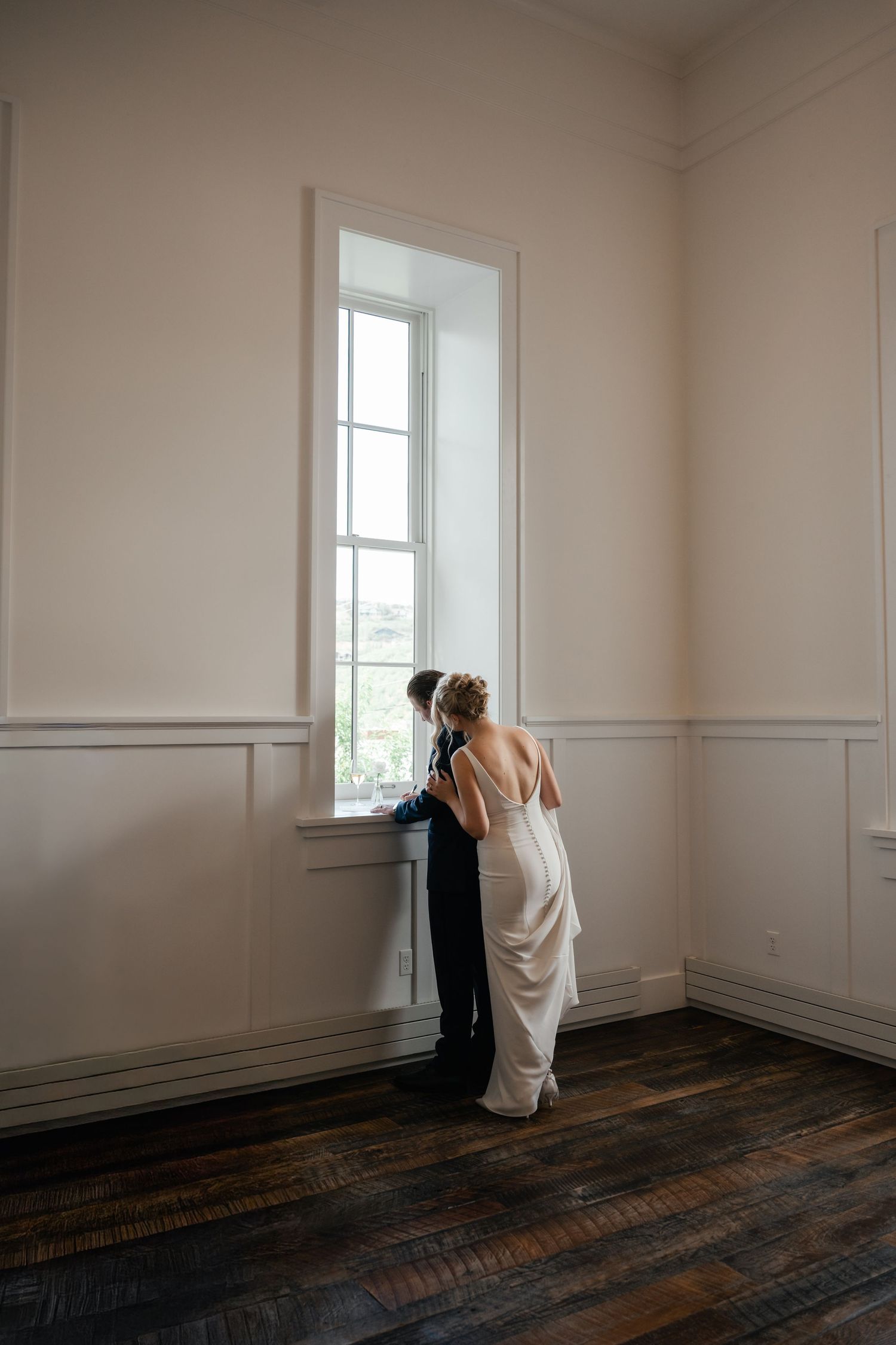 Artistic black and white series showing a bride in a minimalist room with white walls and wooden floors.