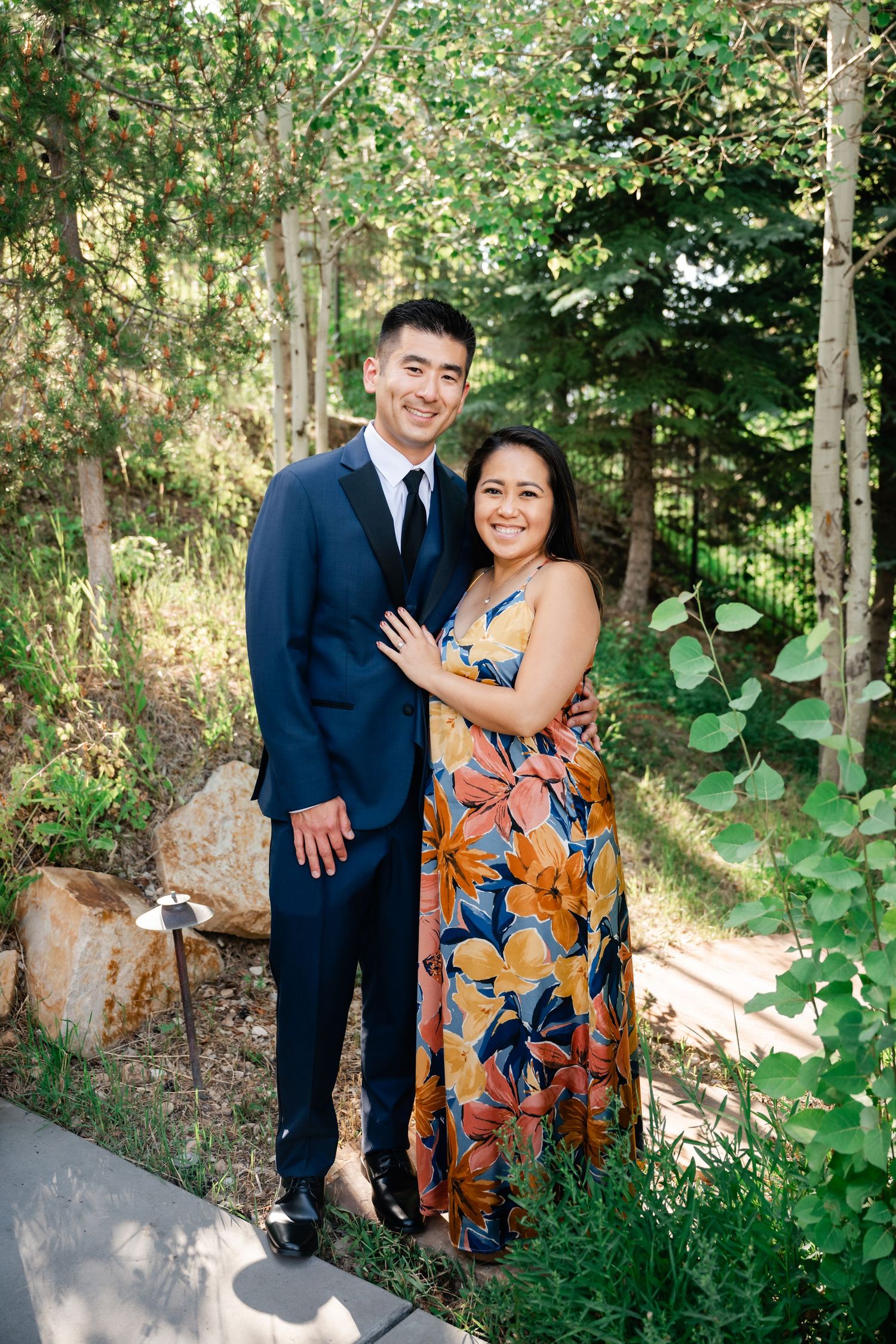 Couple posing for outdoor portraits in a lush green forest setting.