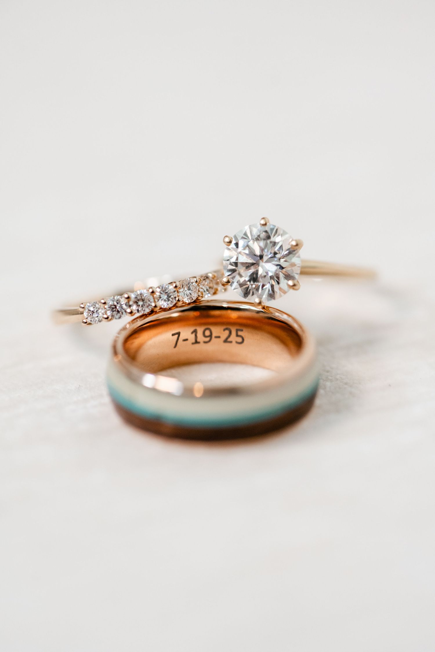 Close-up detail of an elegant diamond engagement ring with a rose gold band and engraved date.