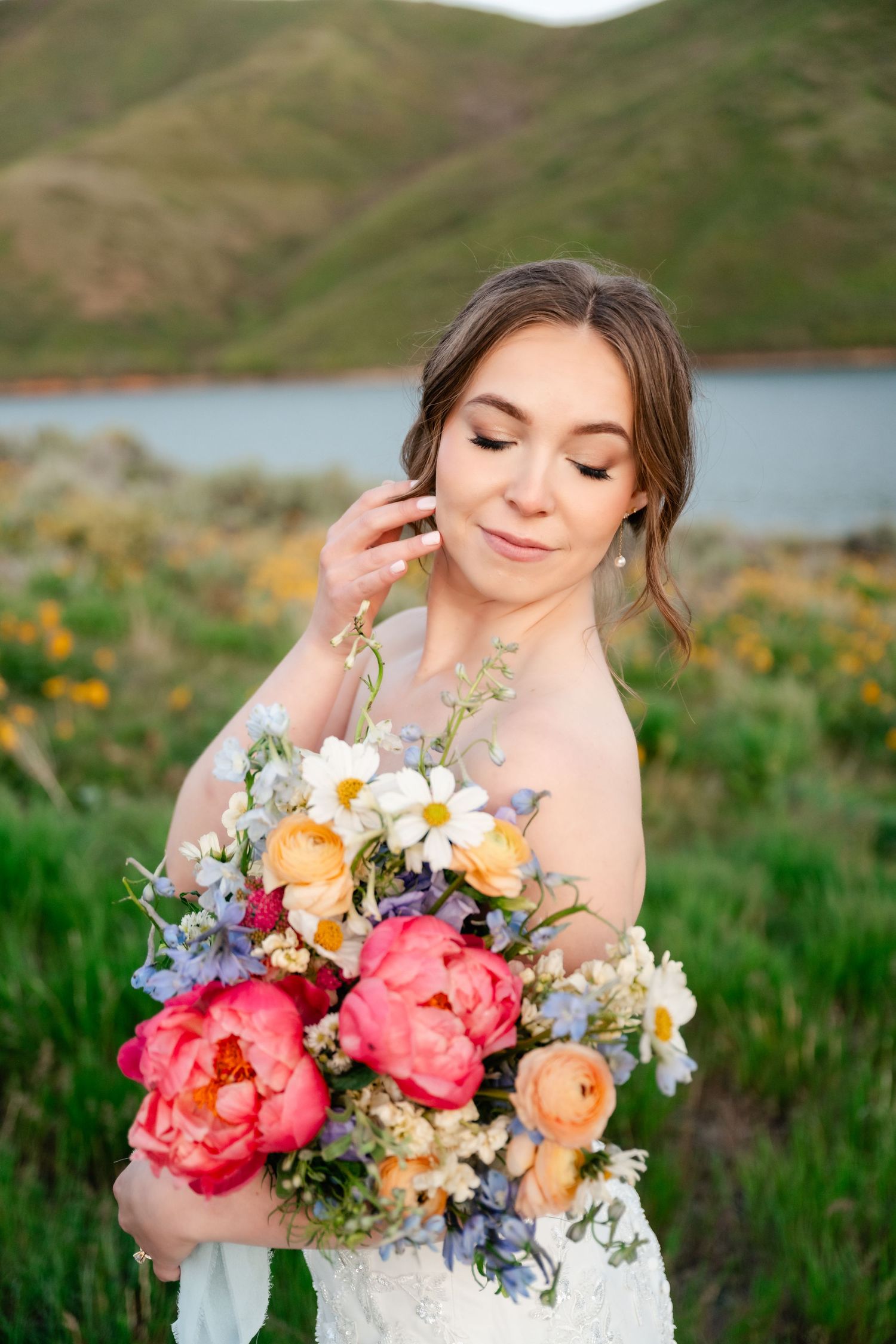 Vibrant coral and peach wedding bouquet with mixed flowers photographed in a mountain setting.