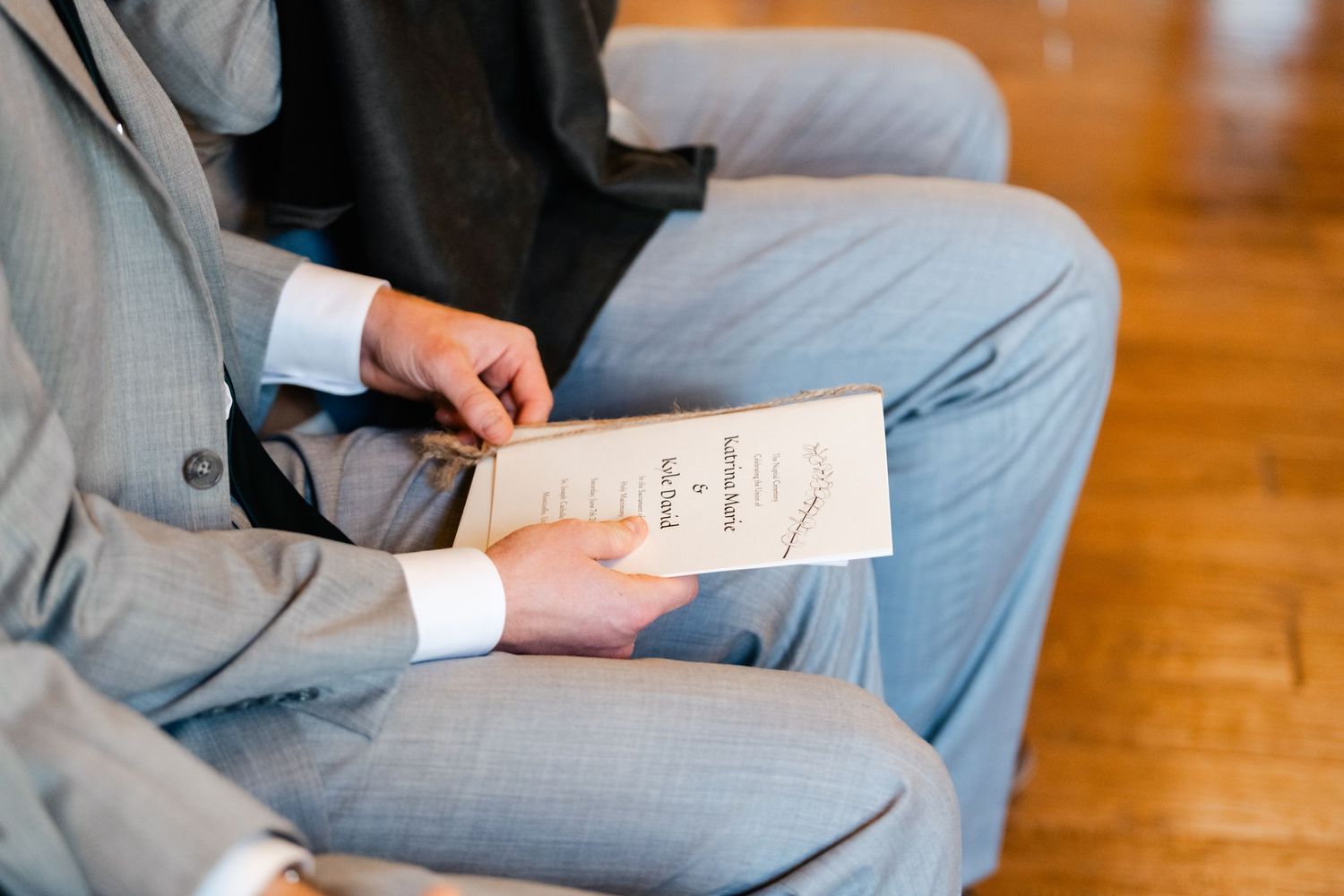 Close-up of hands holding paper programs during wedding ceremony.