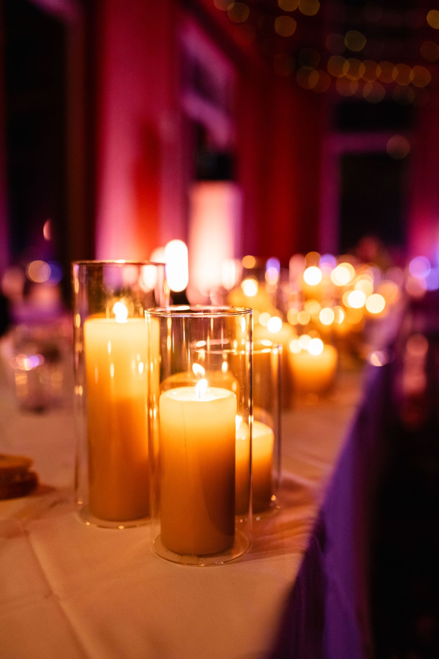 Romantic candlelit table settings create warm ambiance at an evening reception.