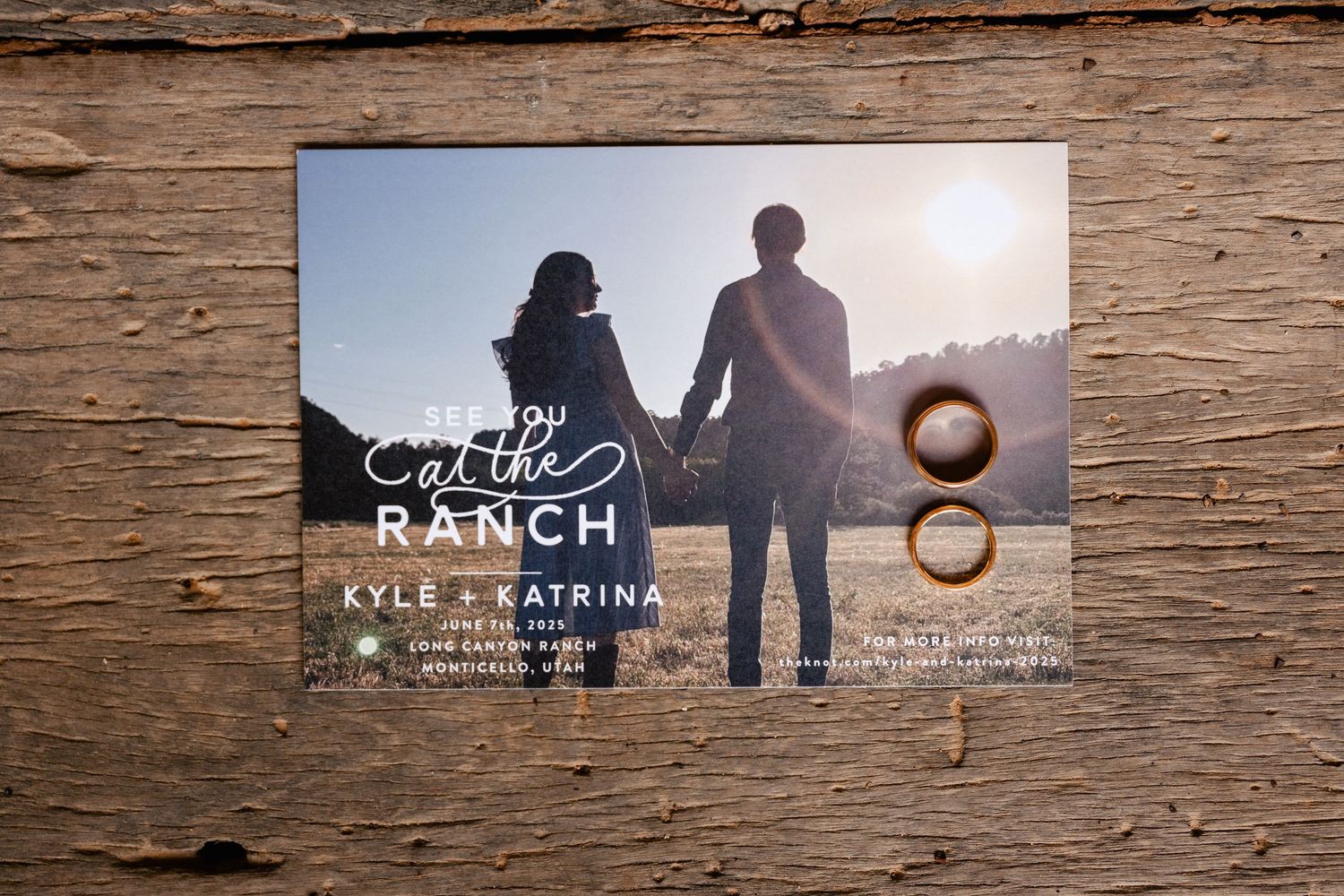 Wedding invitation displayed on rustic wooden background with couple silhouette design.