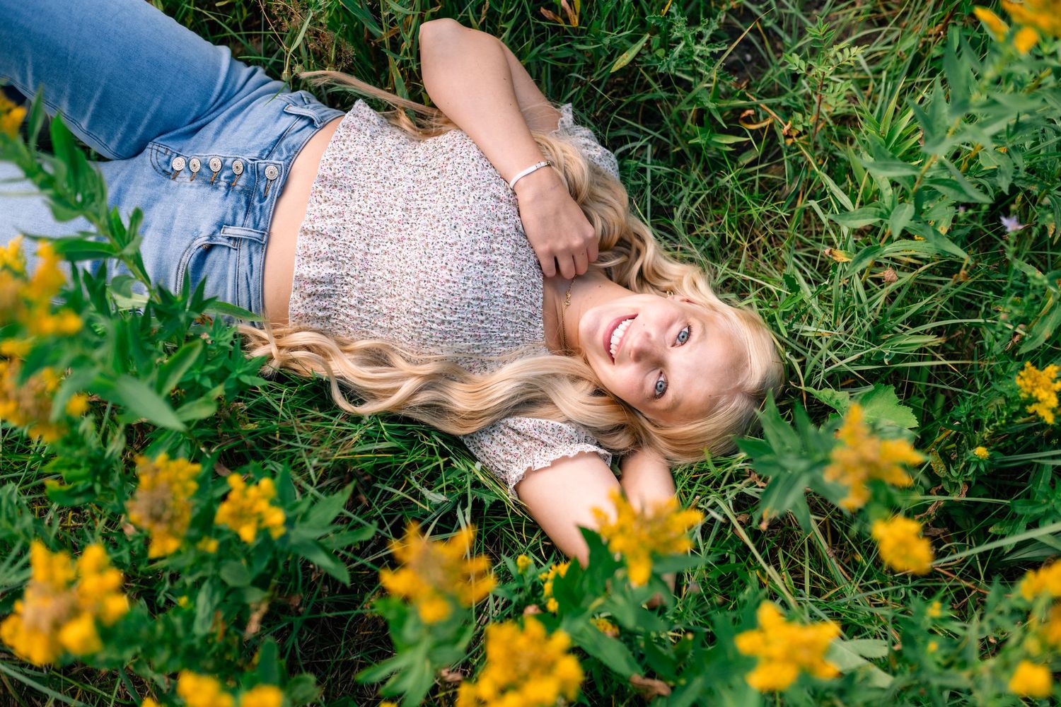 Senior girl lying in a meadow of yellow wildflowers in American Fork Canyon
