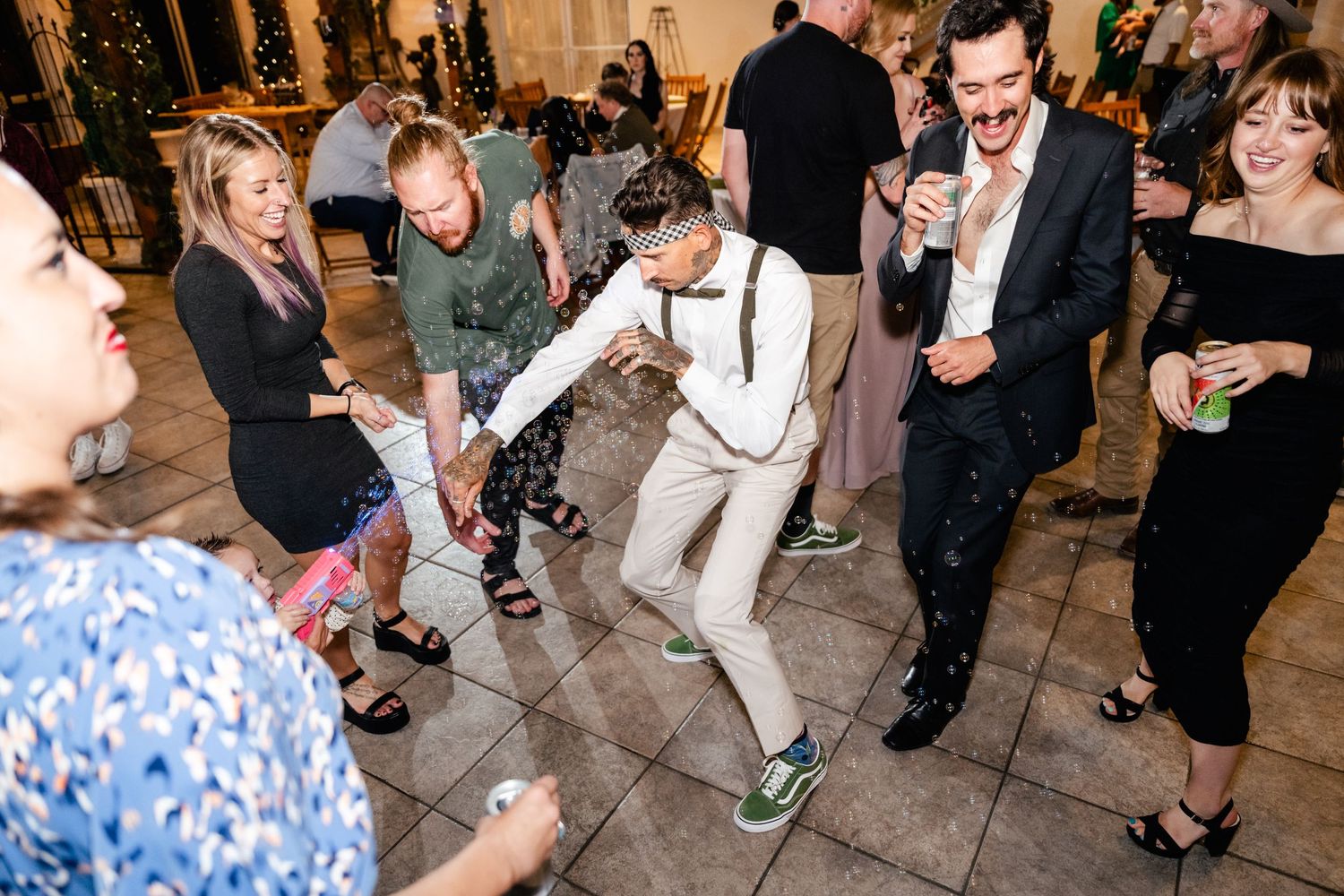 Guests dancing and celebrating at a lively wedding reception with people gathered on a dance floor.