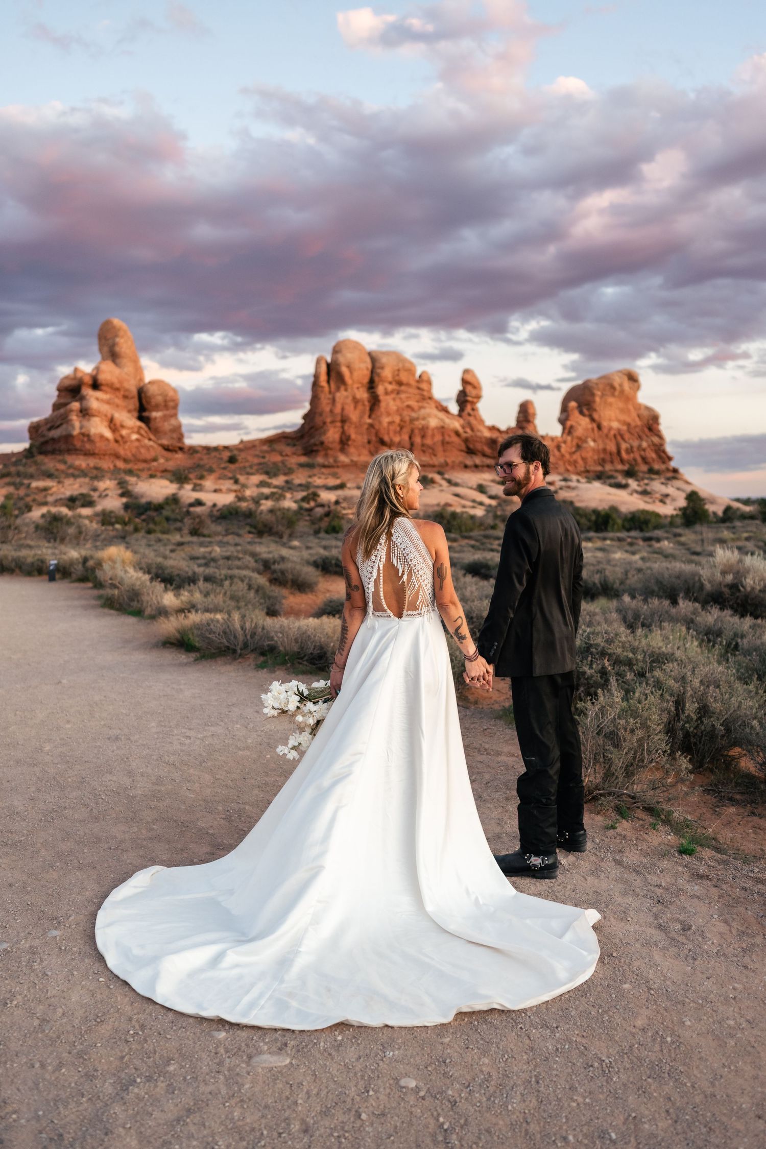 Elopement couple hold hands in Arches National Park by Utah Elopement Photographer and videographer