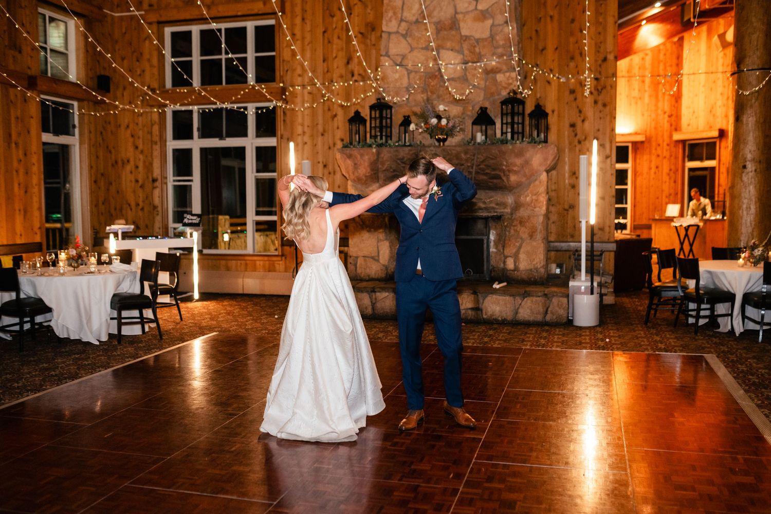 A couple shares their first dance in an elegant rustic venue with stone walls and warm lighting. Utah Wedding Photographer. Park City Wedd.