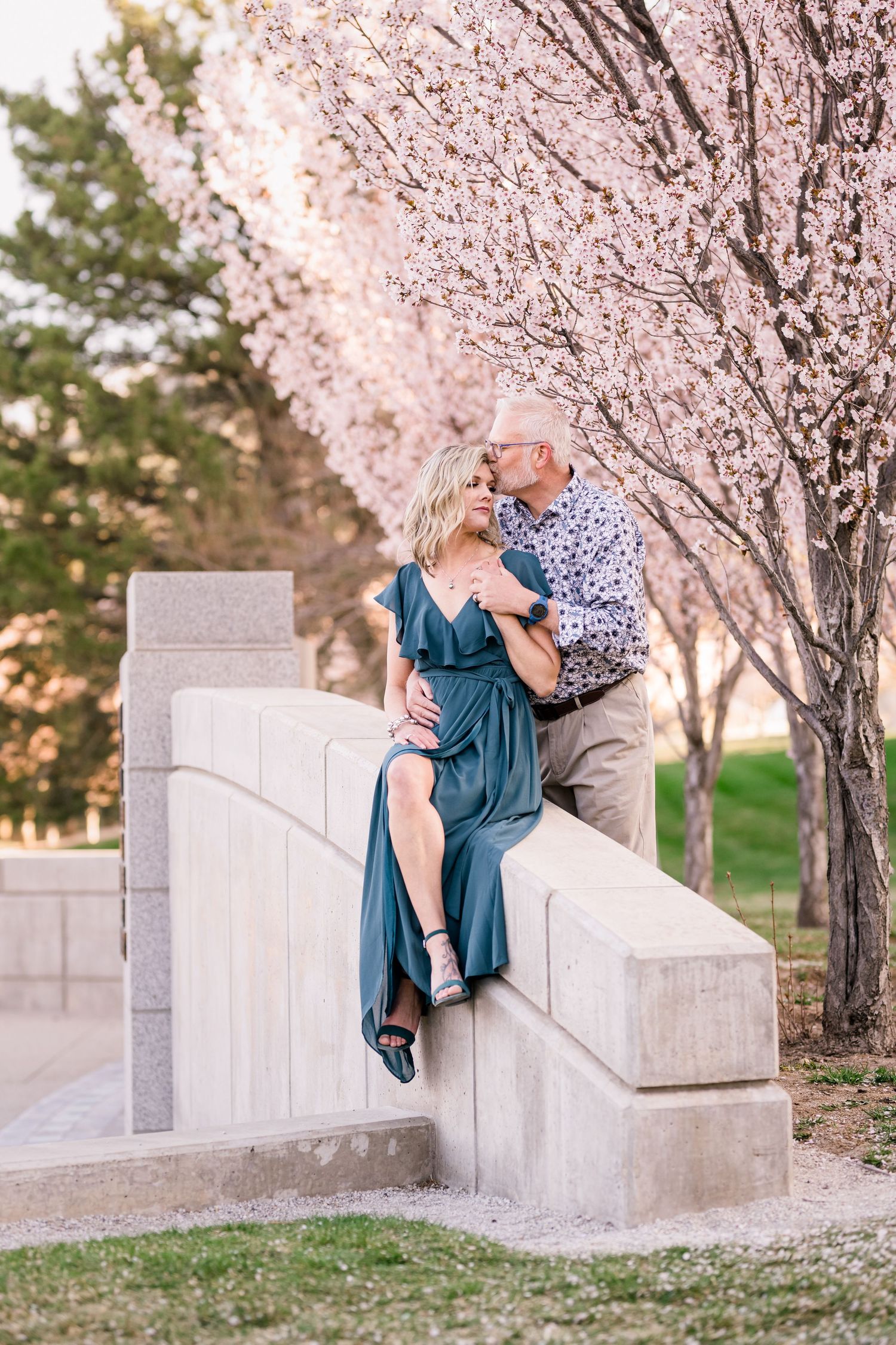 A romantic moment captured under blooming cherry blossom trees near stone steps.