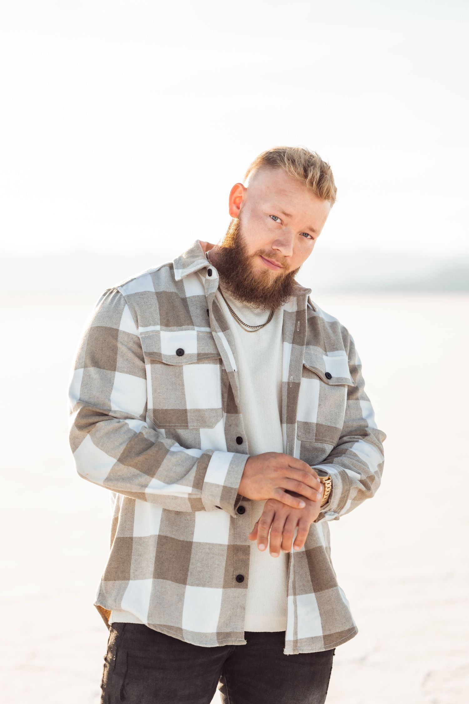 Utah Salt Flats Photographer. Person in plaid flannel shirt and white tee poses casually on bright natural backdrop.