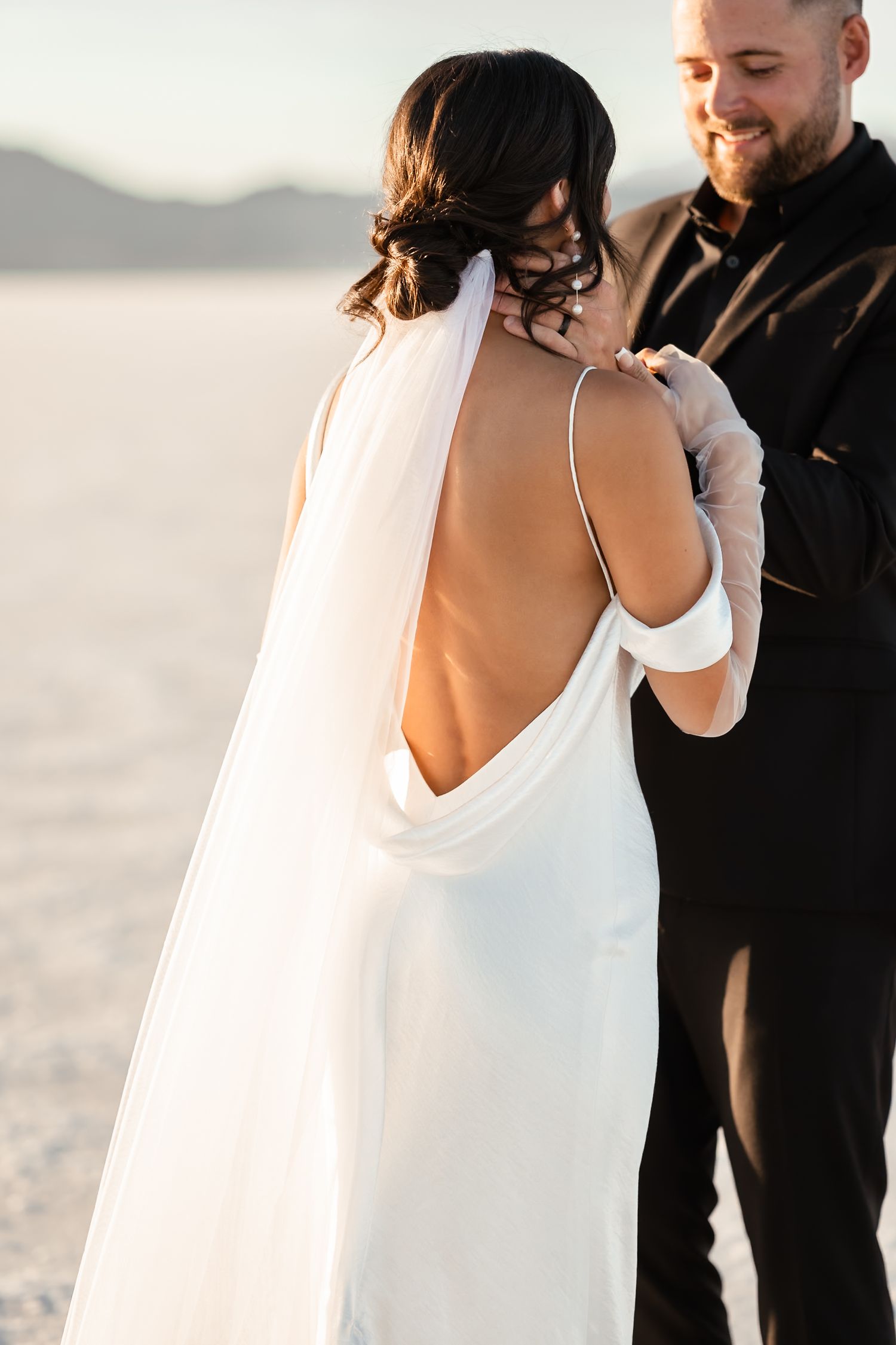 An intimate wedding moment captured on the salt flats with flowing white dress details.