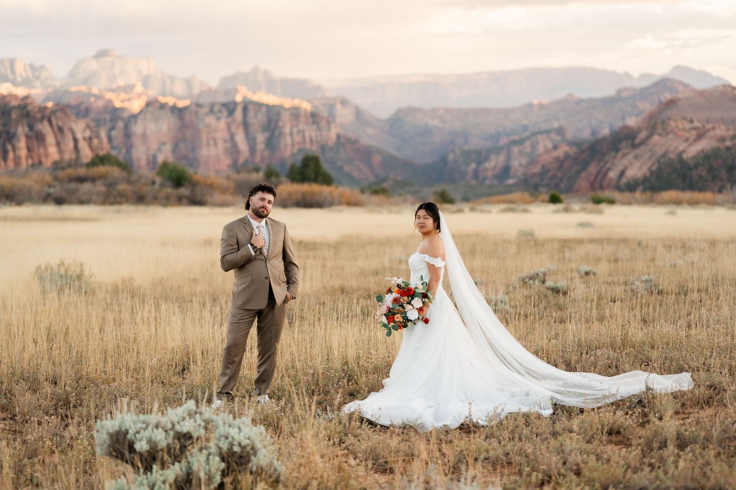 A couple shares a romantic moment in a scenic mountain meadow during their wedding photo session.