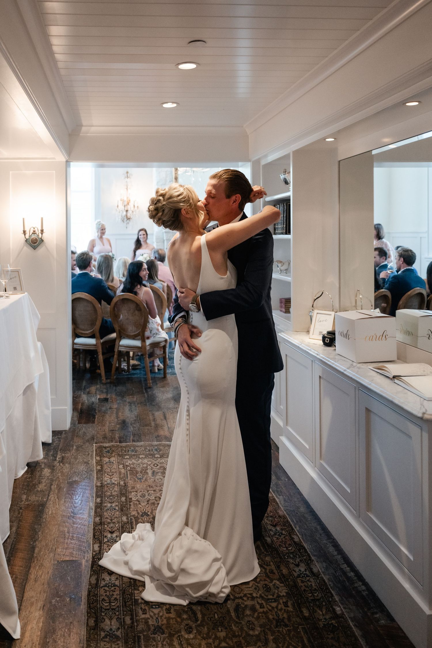 Wedding couple dancing in bright white room with wainscoting and hardwood floors.