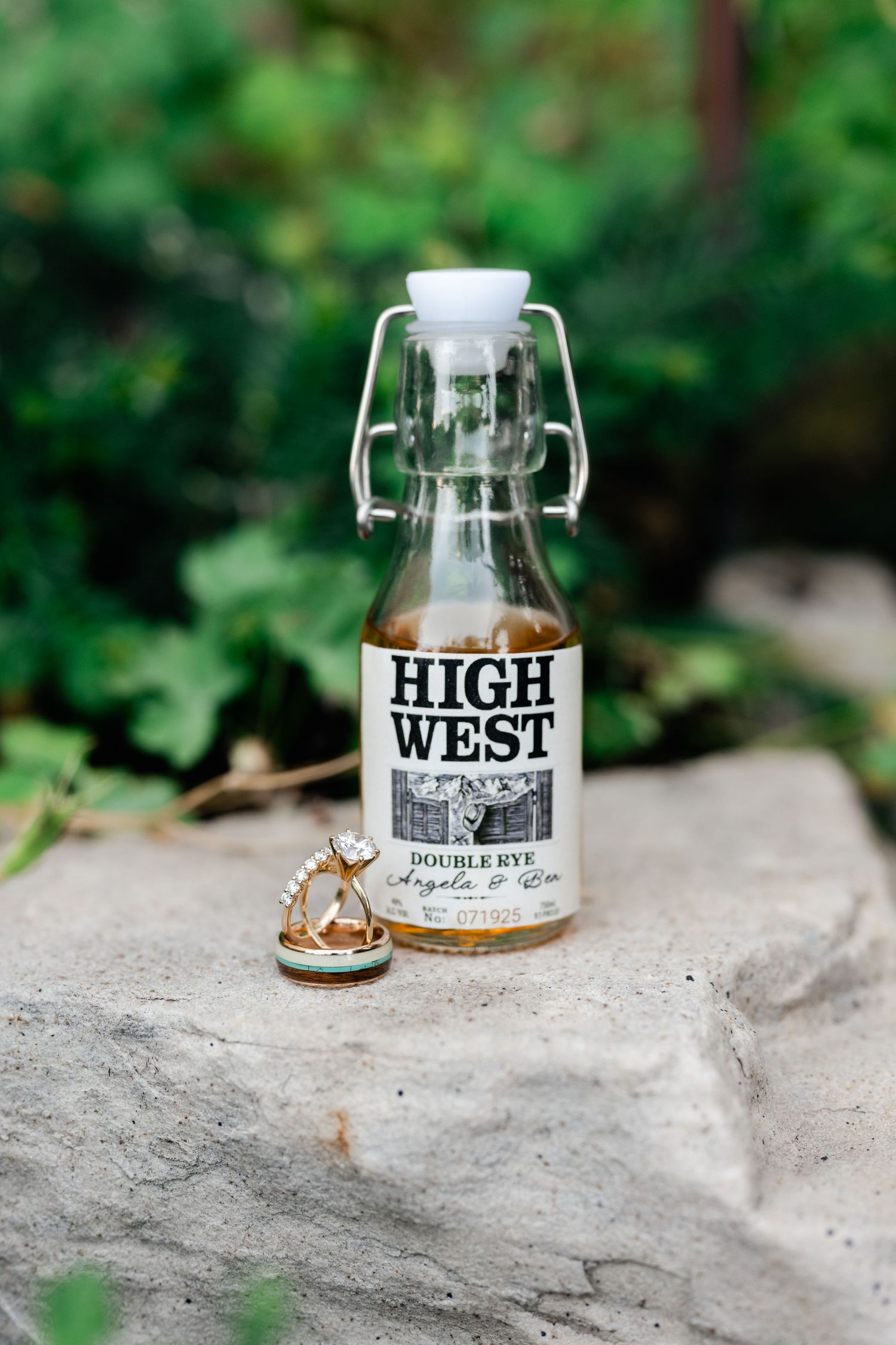 High West whiskey bottles arranged on stone surface with natural green background.