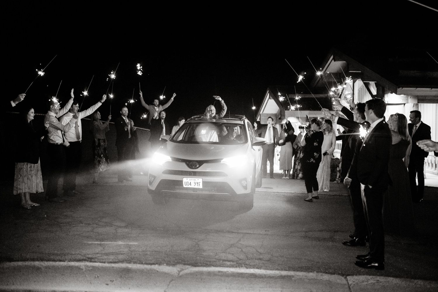 Night time wedding exit with car headlights illuminating the scene.