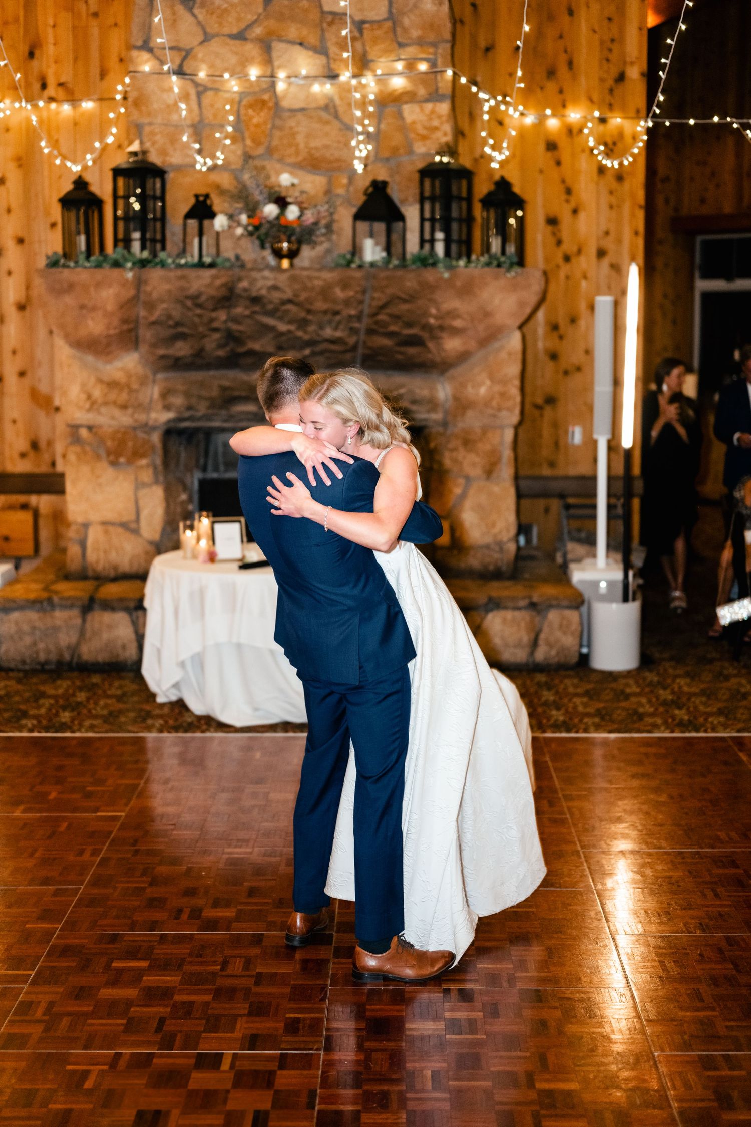 A romantic first dance in a rustic venue with stone walls and twinkling string lights.