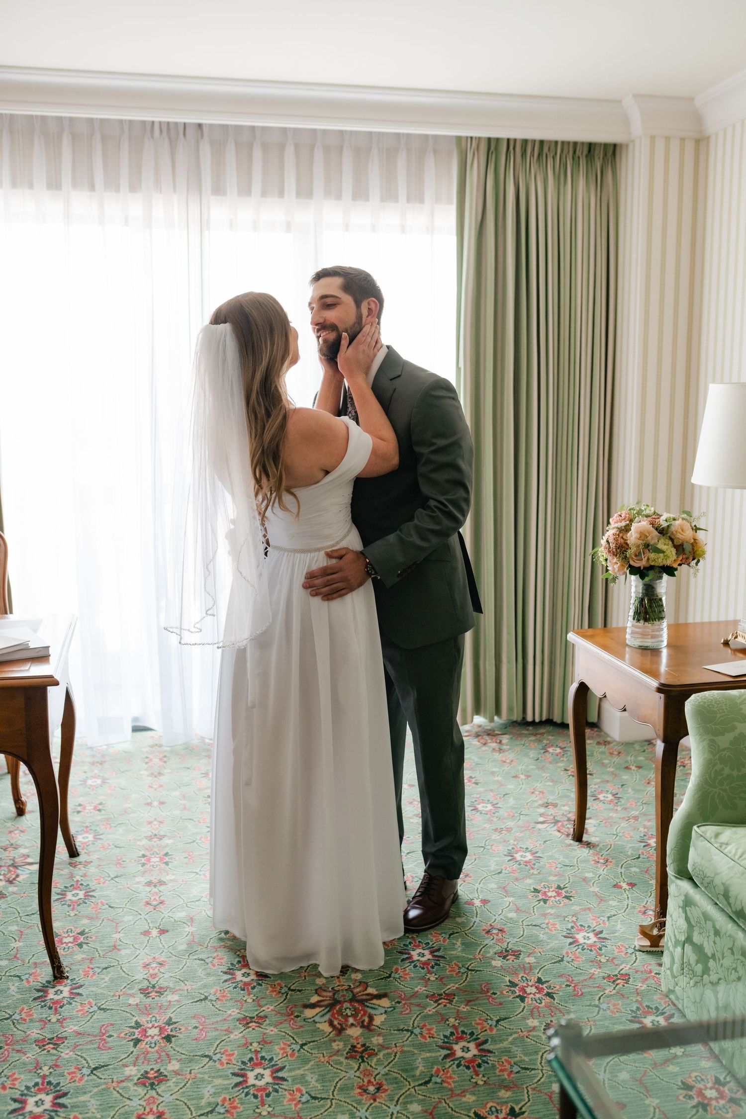 A series of playful first look photos showing a couple meeting in a hotel room with floral carpeting.