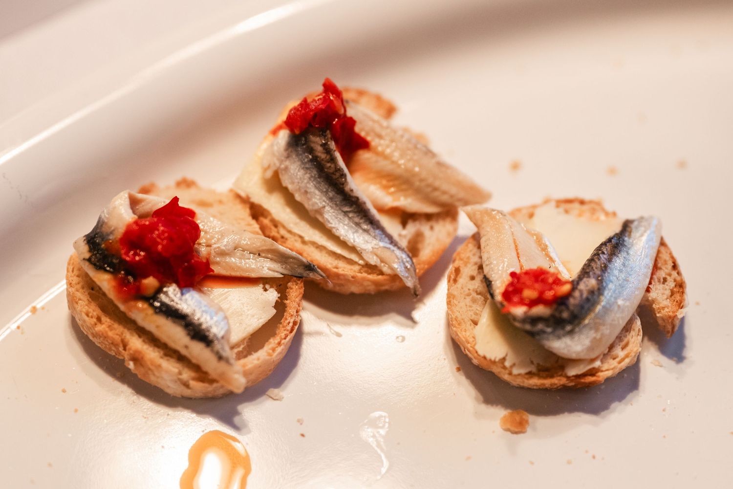 Appetizer bites with red garnish served on small plates in a sequence.