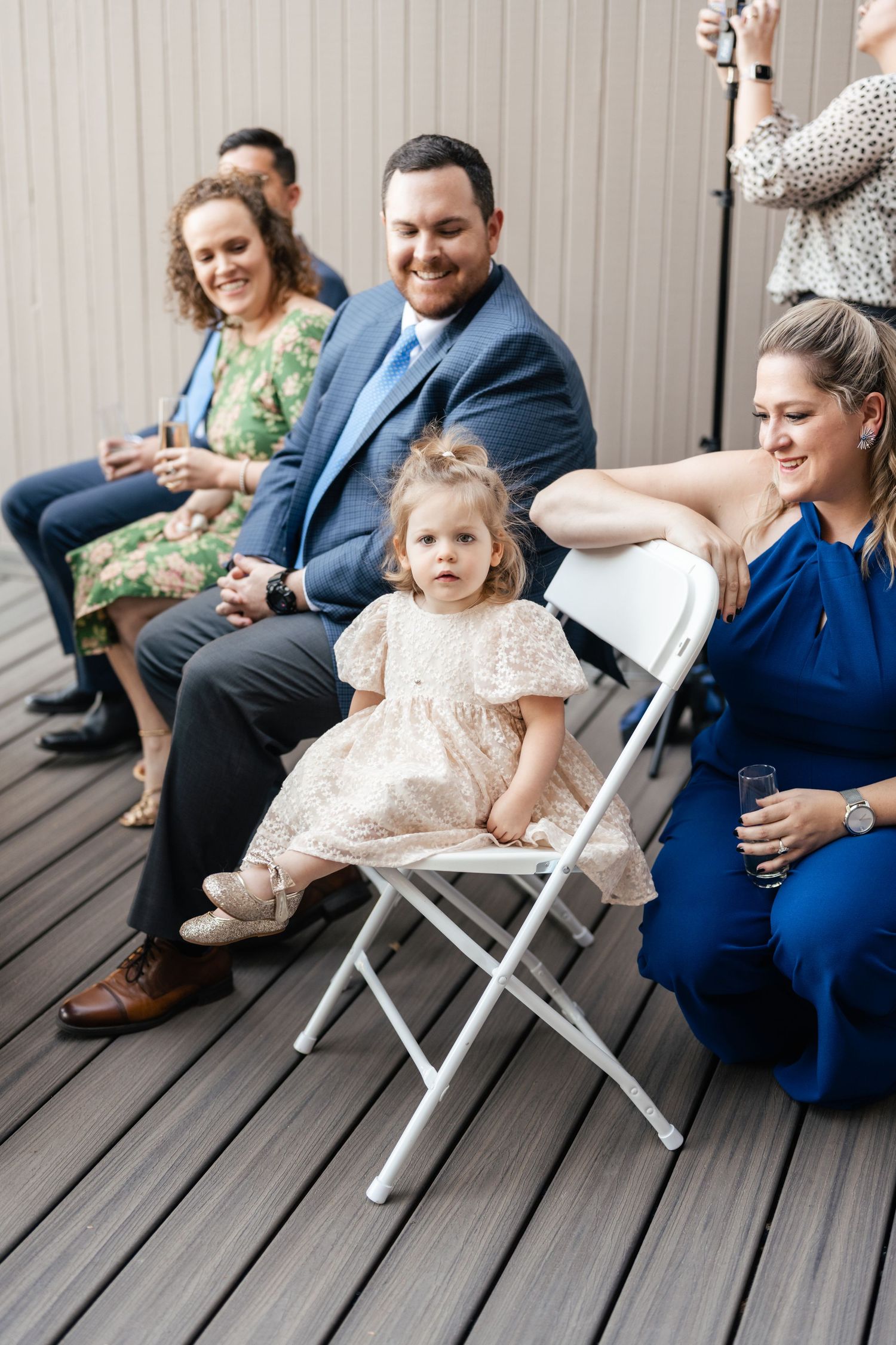 A sequence of candid moments shows guests sitting on wooden deck chairs during an outdoor gathering.