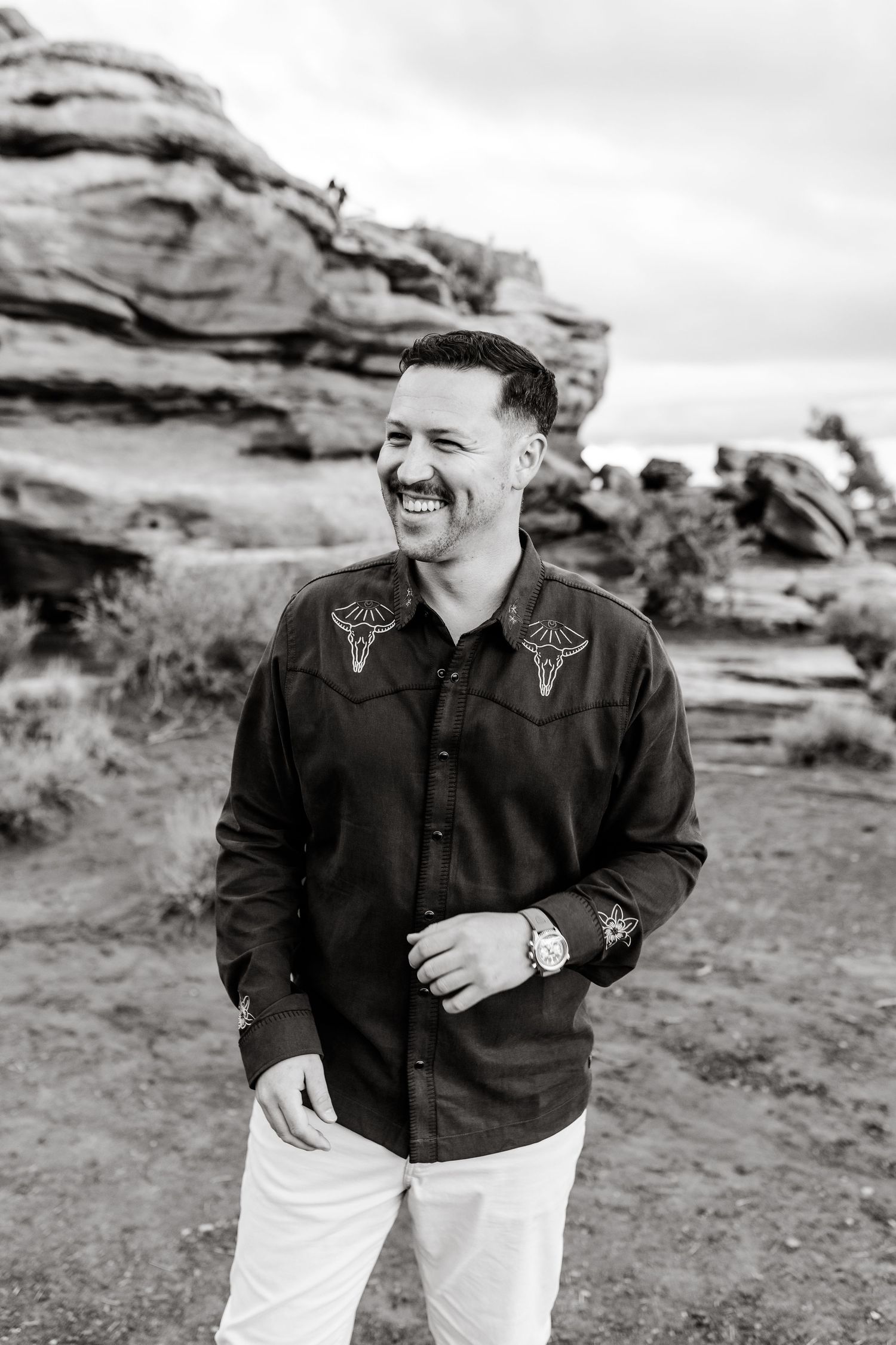 Black and white portrait session on desert rocks with dramatic cloudy backdrop.