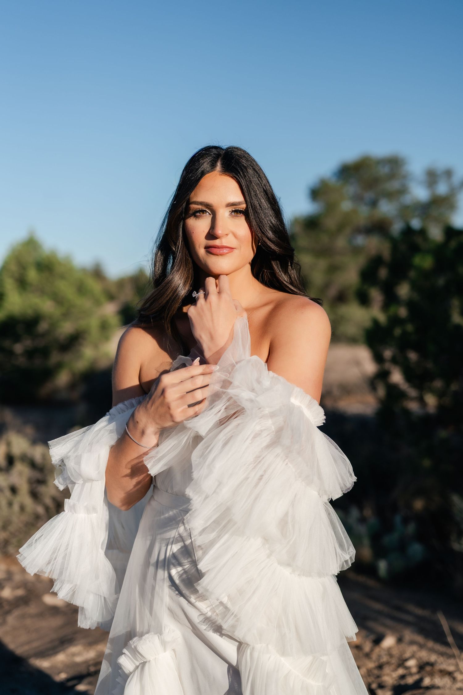 Zion Adventure Session. A bride in a flowing white dress with ruffled details poses against a desert landscape.