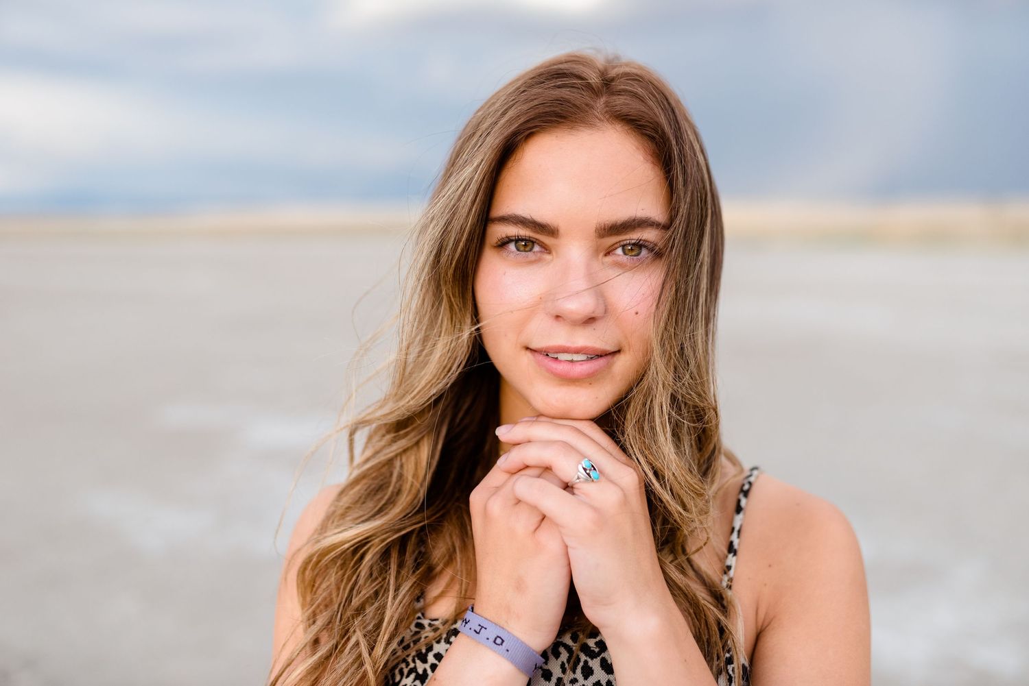 A series of outdoor beach portraits showing a person with long brown hair in casual attire against a sandy backdrop.