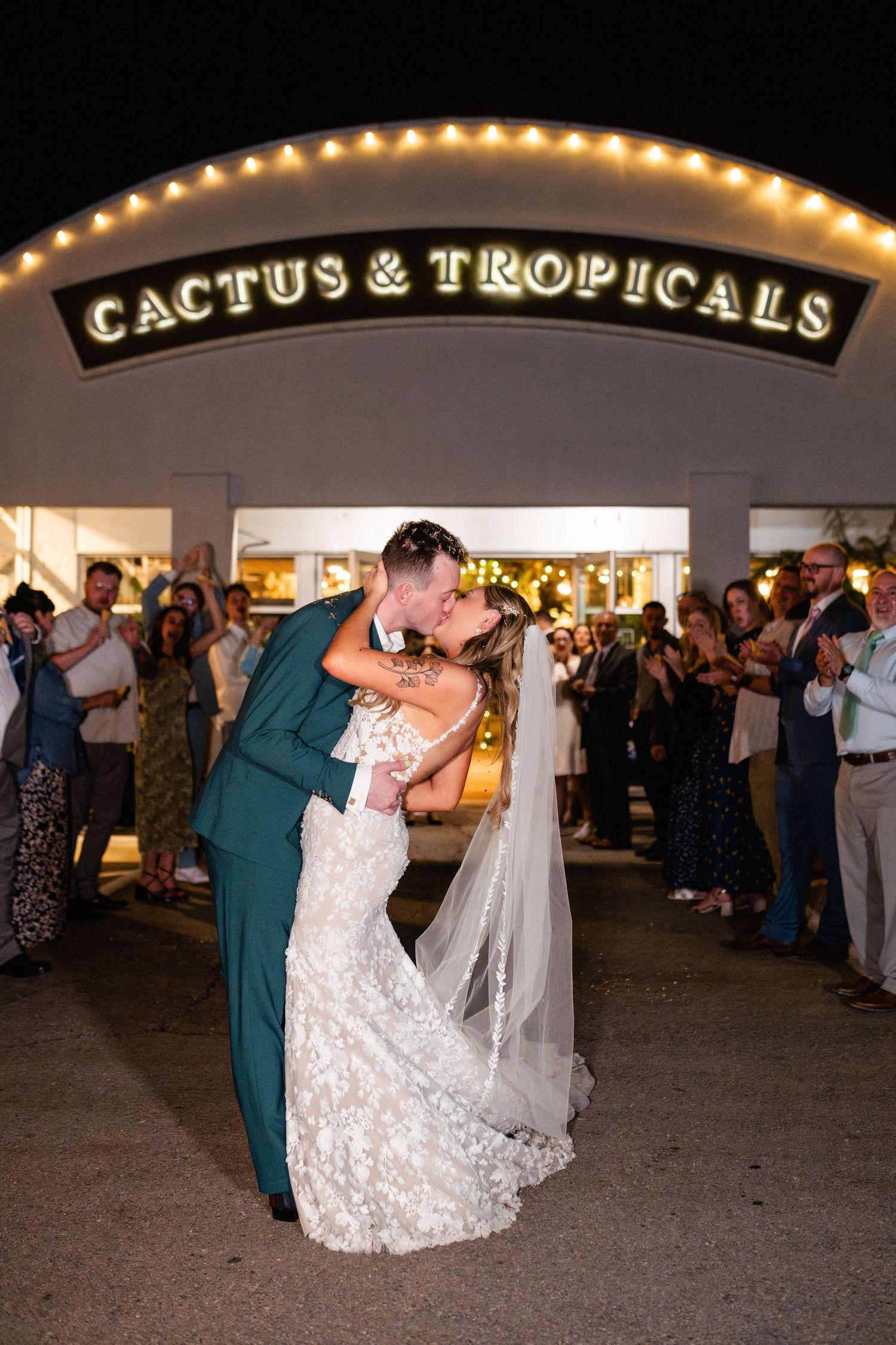 A couple shares a romantic wedding send off of dried flower petals at Cactus & Tropicals while guests watch and celebrate.
