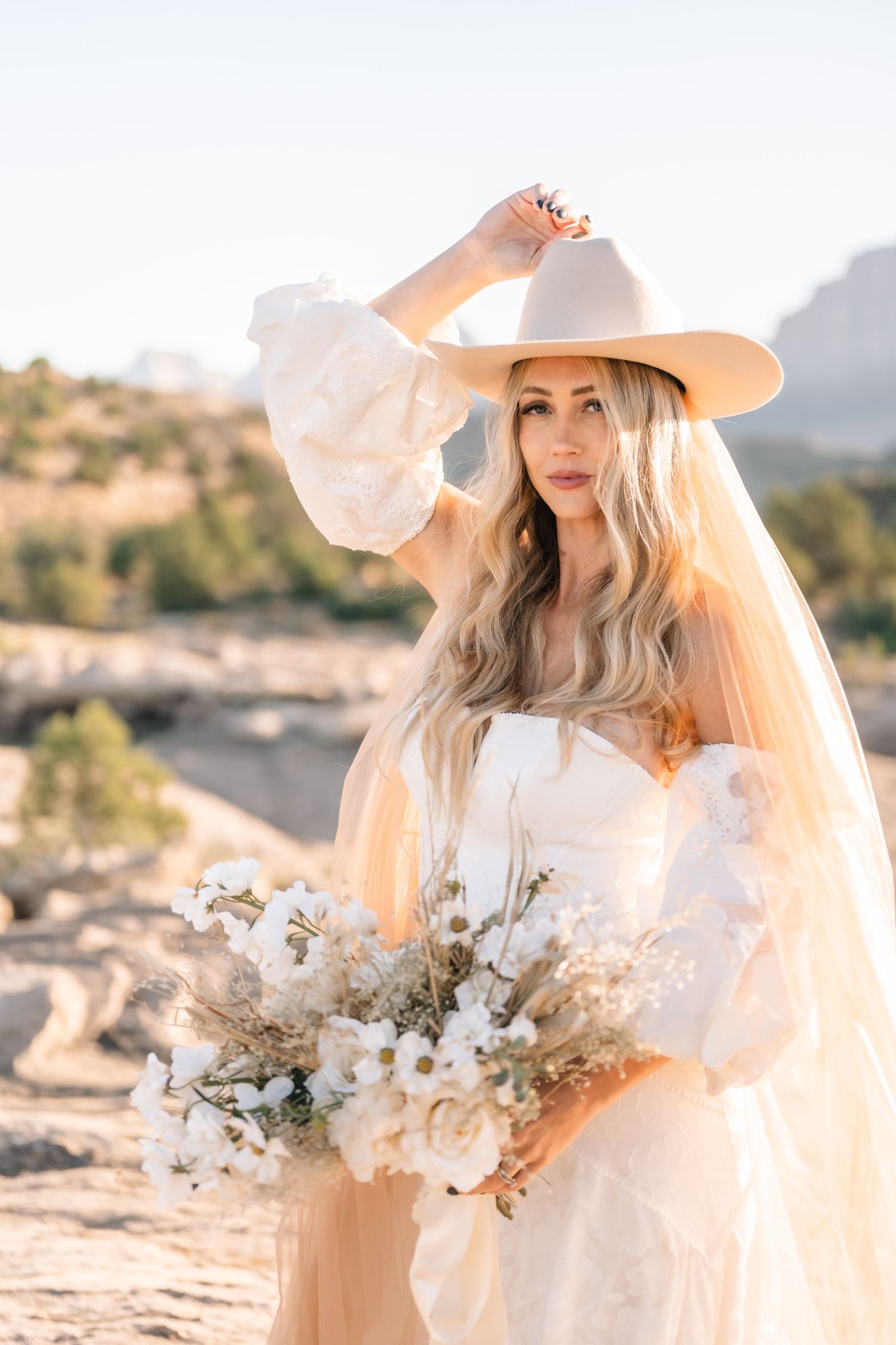 Utah elopement photographer takes breathtaking desert sunrise bridal session with a stunning bouquet and cowgirl hat.