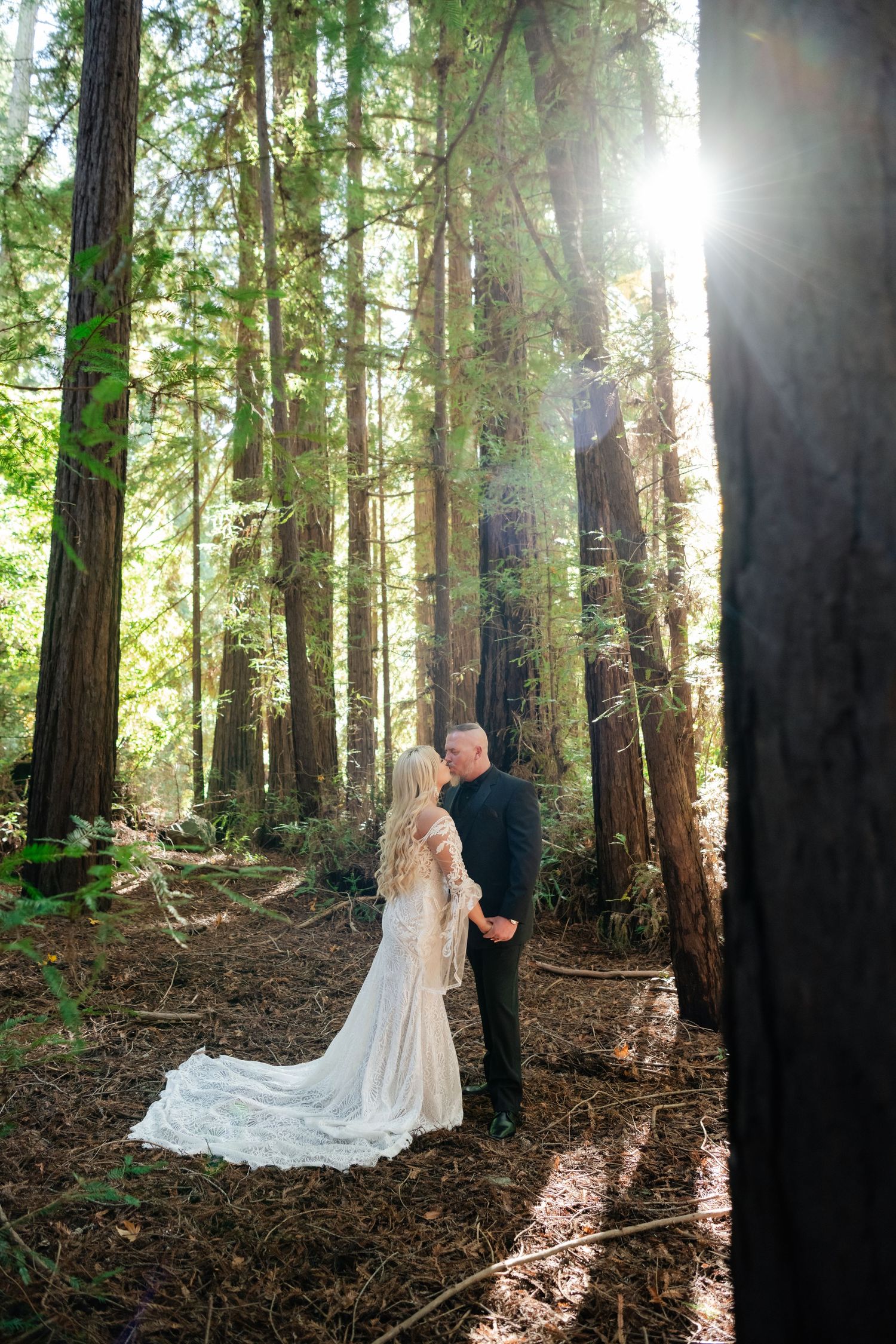 Sunlit forest wedding scene with tall redwood trees creating a natural cathedral effect.