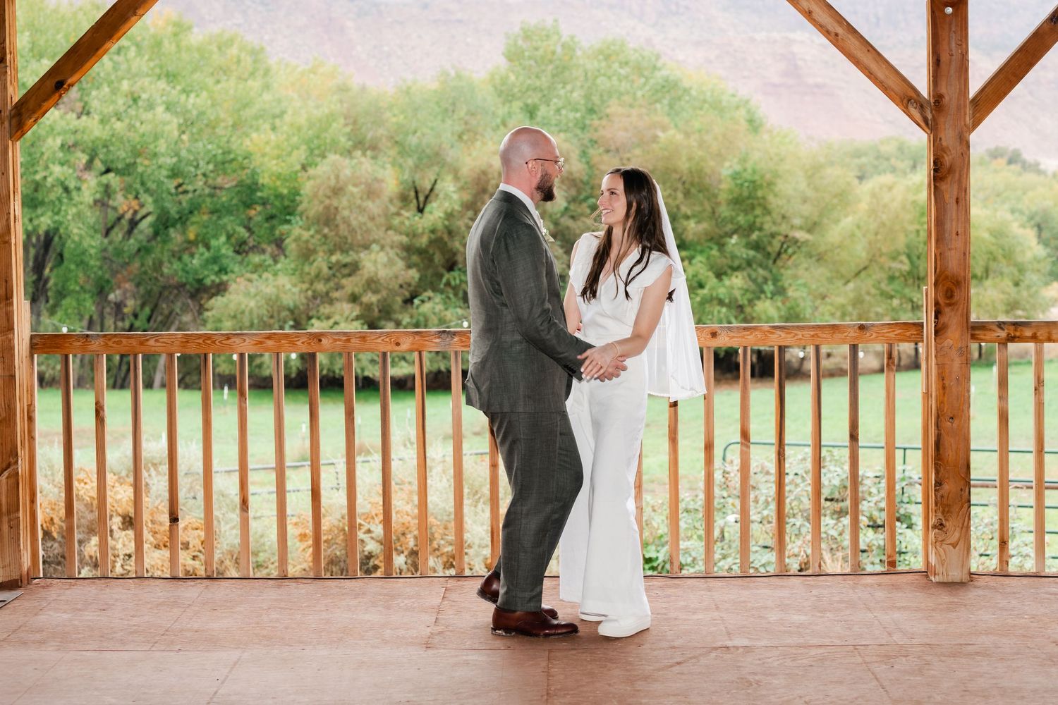 Wedding celebration on a rustic wooden deck overlooking scenic mountain landscape.